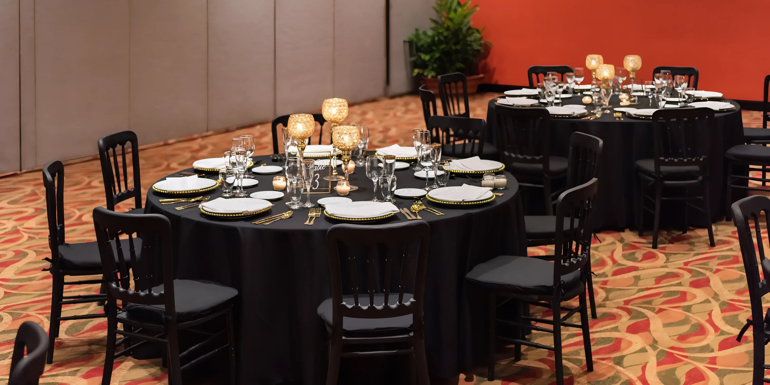 Elegant banquet hall setup with round tables, black chairs, and formal table settings at Hyatt Ziva Puerto Vallarta.