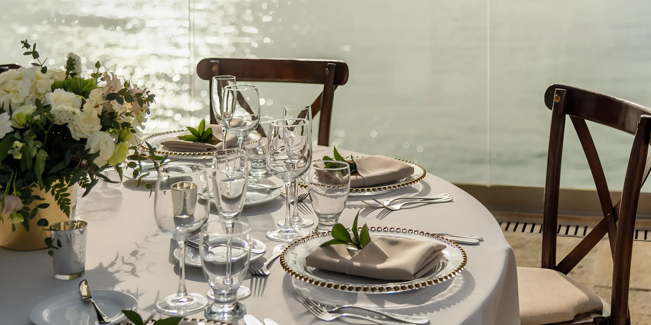 Elegant table setting by the water at Hyatt Ziva Puerto Vallarta for a special event with sunlight reflecting off the glasses.
