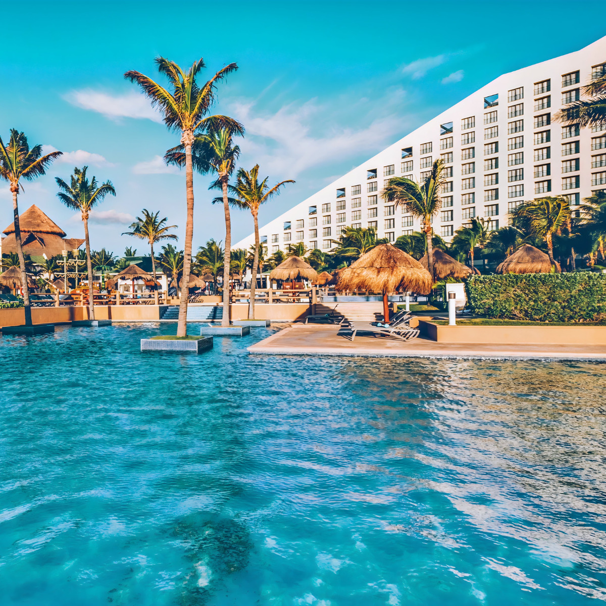 A wedding at Iberostar Selection Cancun with palm trees and a hotel in the background.