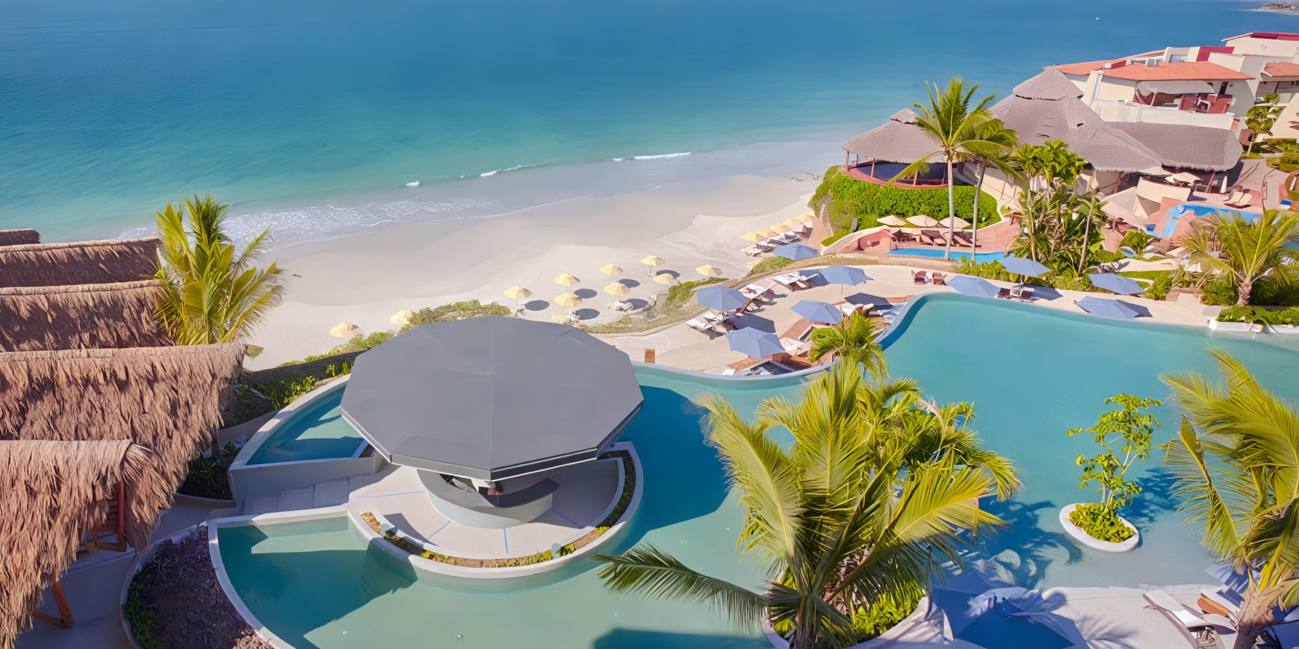 Aerial view of Marival Armony, a beach resort featuring a large pool with a swim-up bar, surrounded by palm trees, sun loungers, umbrellas, and a sandy shoreline meeting the turquoise ocean waters.