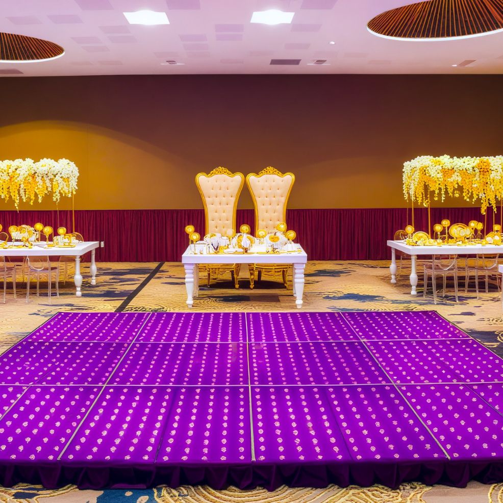 A beautifully adorned event stage featuring two ornate chairs sets the scene for a stunning destination wedding, complemented by a purple-lit dance floor inviting guests to celebrate.