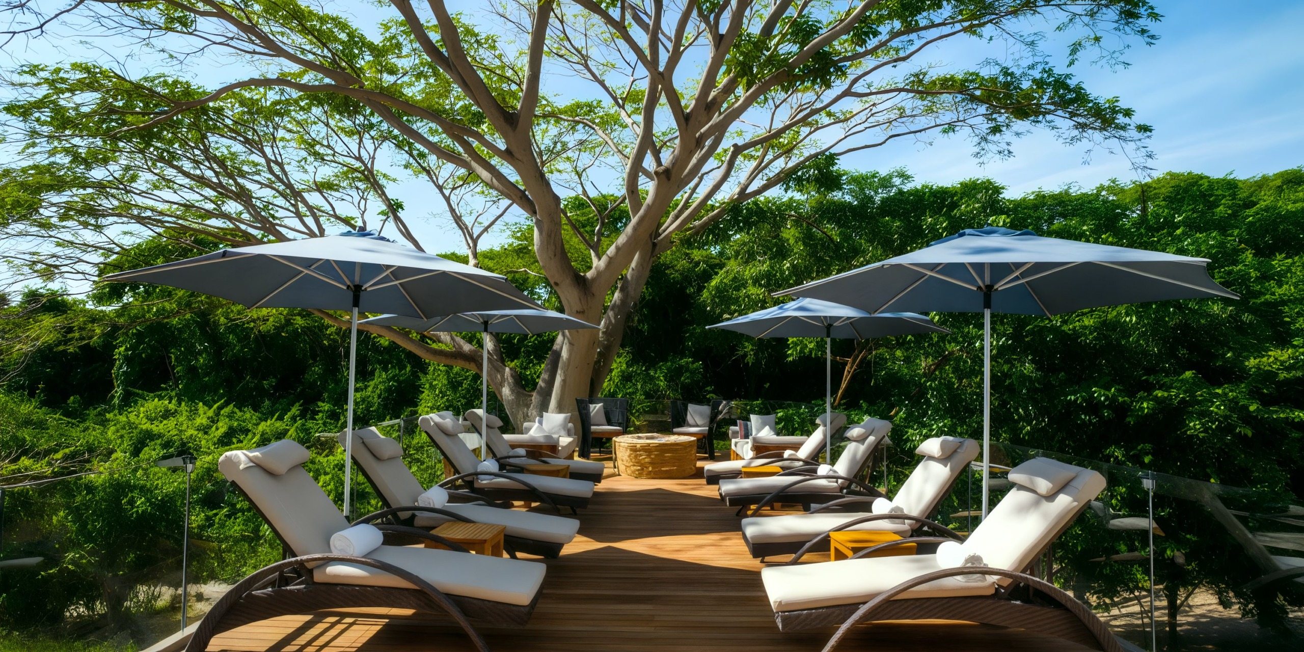 The Marival Armony features sun loungers equipped with umbrellas, all neatly arranged around a fire pit on a wooden deck, encircled by verdant trees.