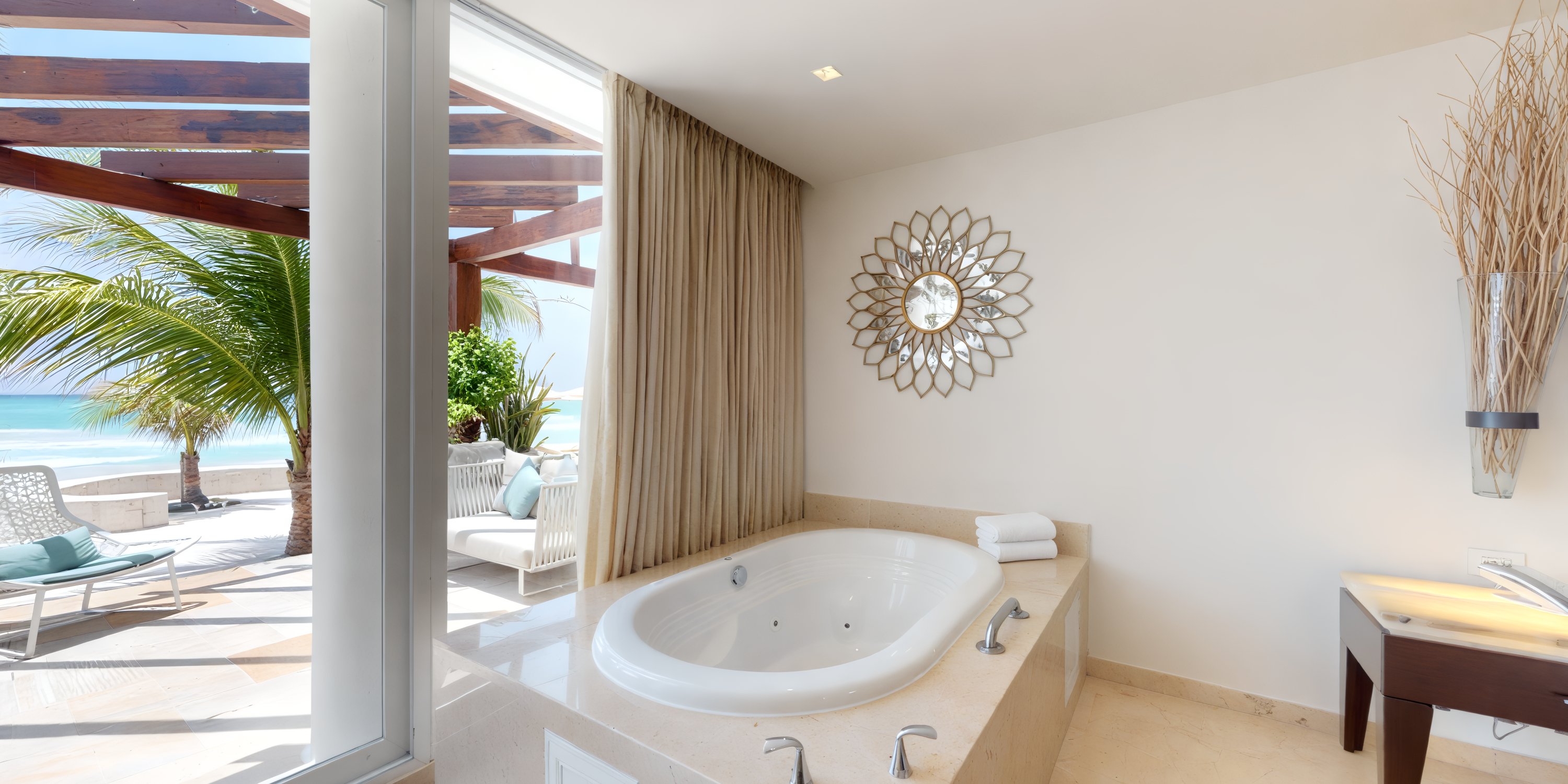 Indulge in the luxurious Playacar Palace bathroom, where you can unwind in an ocean-view bathtub perfect for a destination wedding retreat, with an adjoining patio that offers comfortable seating for intimate moments.