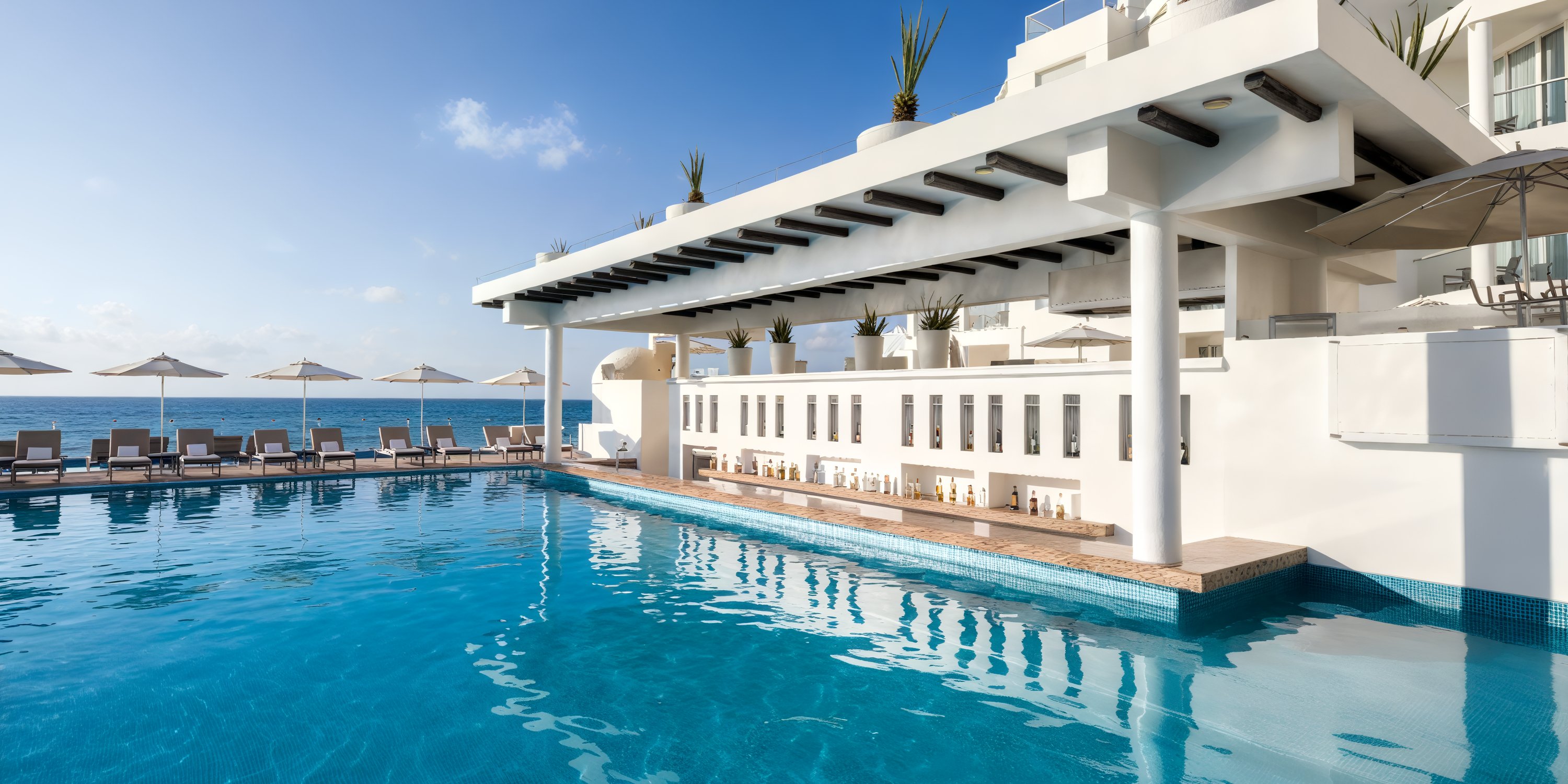 Playacar Palace offers an outdoor pool complete with loungers and features a covered bar area by the ocean, making it an ideal location for a destination wedding.