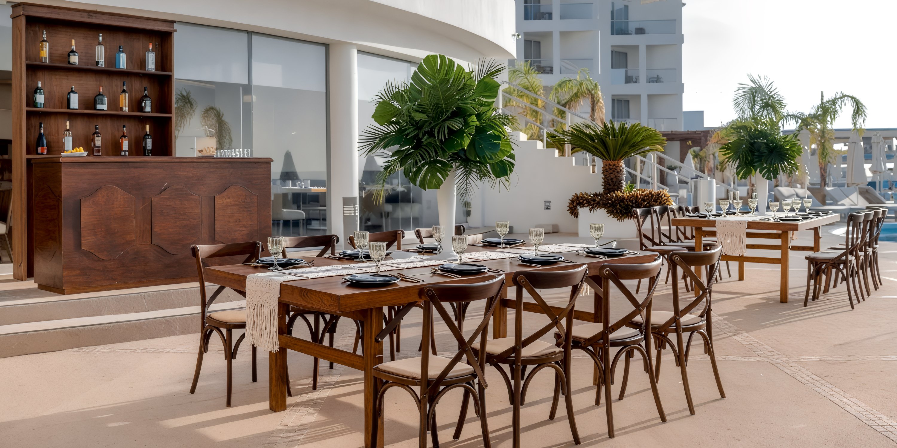The outdoor dining area at Playacar Palace, adorned with wooden furniture and tropical plants, provides a stunning setting perfect for a destination wedding.