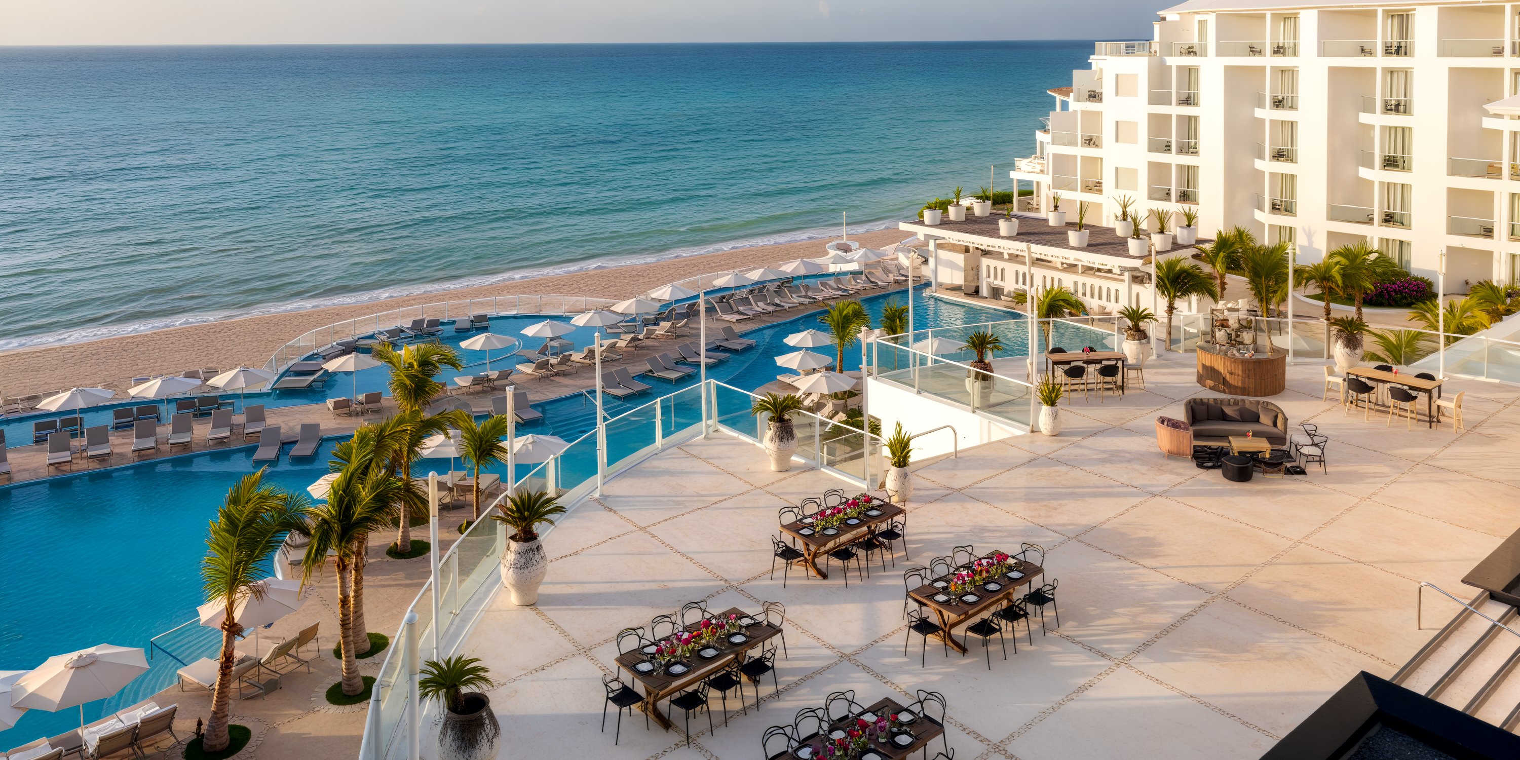 Playacar Palace: a beachfront resort perfect for destination weddings, featuring poolside seating, dining tables, and stunning ocean views.