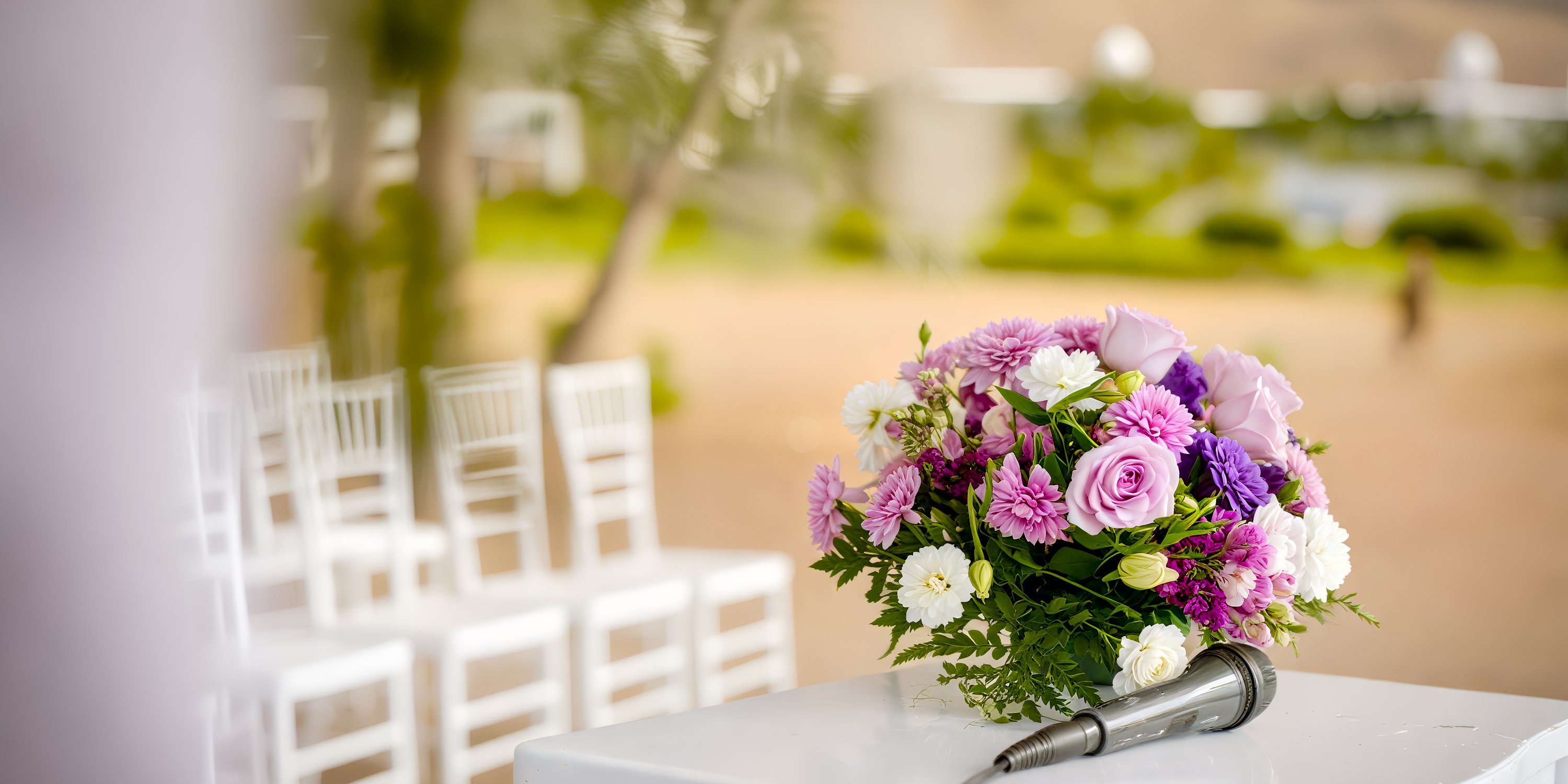 A bouquet of pink and purple flowers sits beside a microphone, ready for the destination wedding ceremony at Hotel Riu Guanacaste.