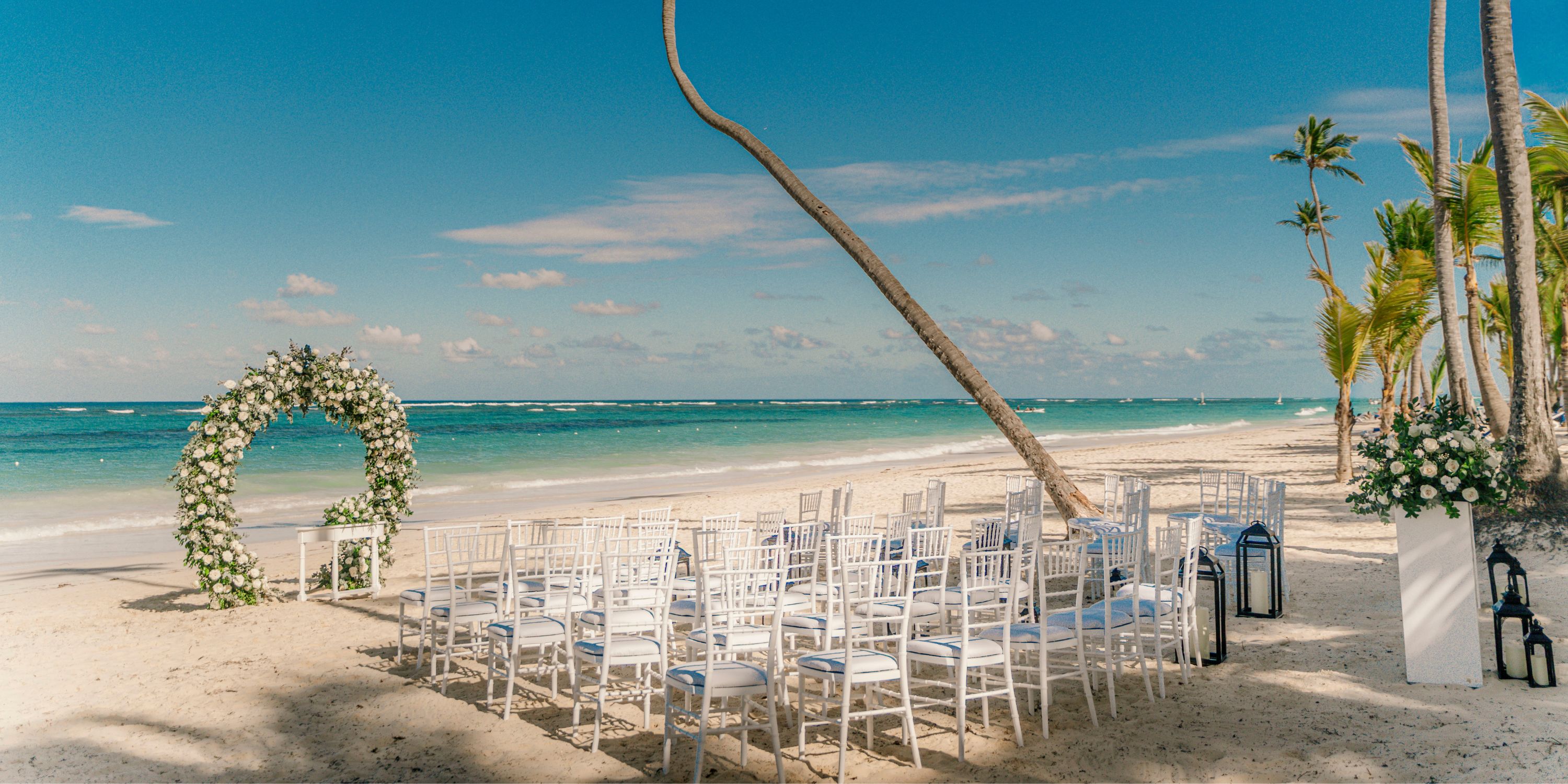 White chairs and a floral arch prepared for a destination wedding at Hotel Riu Palace Bavaro.