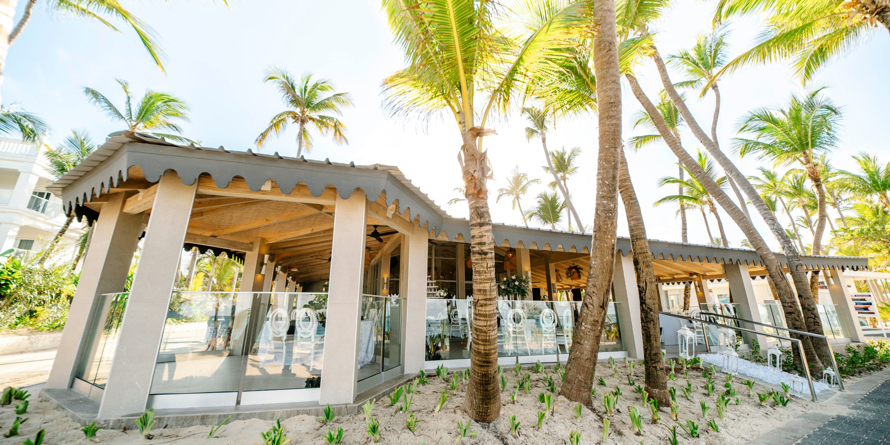 Hotel Riu Bambu: Outdoor restaurant with glass railing, palm trees—ideal for a destination wedding.