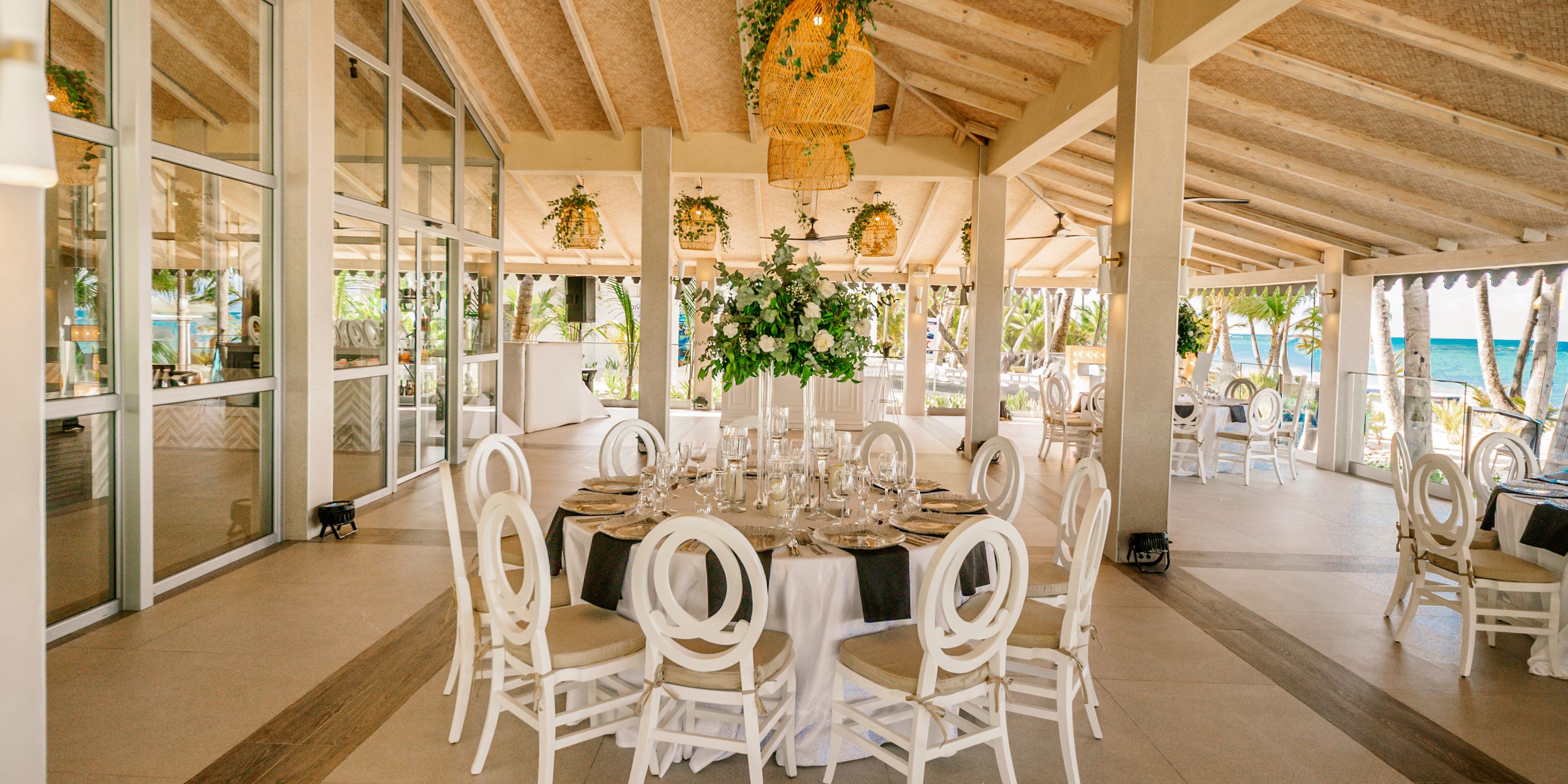 Hotel Riu Palace Macao features elegant indoor-outdoor dining, perfect for destination weddings, with round tables and white chairs.
