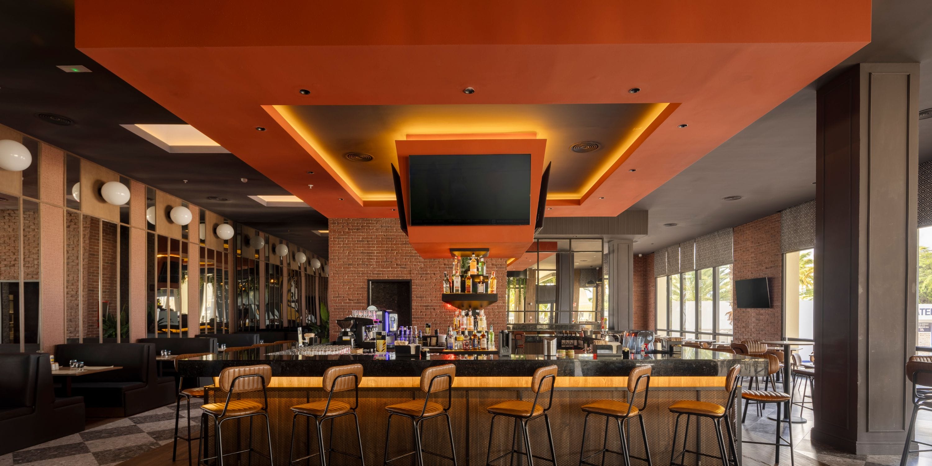 Hotel Riu Palace Aruba bar—ideal for a destination wedding, high stools, TVs, and orange lighting.