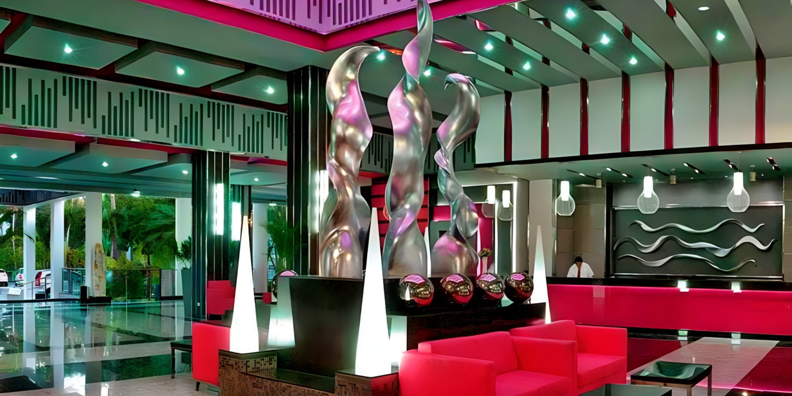 The lobby of Hotel Riu Yucatan, perfect for a destination wedding, with pink chairs and a large sculpture.