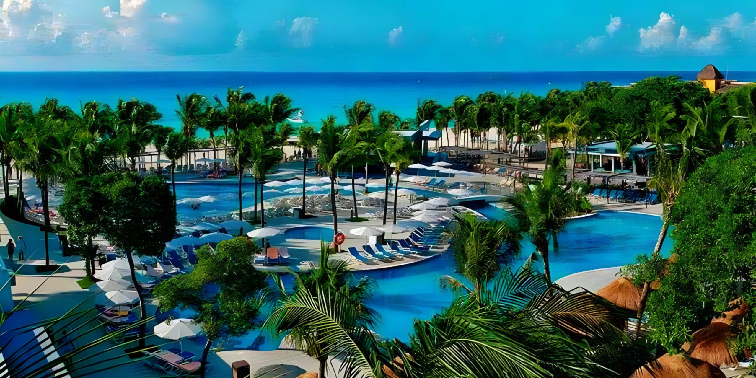 An aerial view of Hotel Riu Yucatan, a perfect destination wedding venue, with a pool and palm trees.
