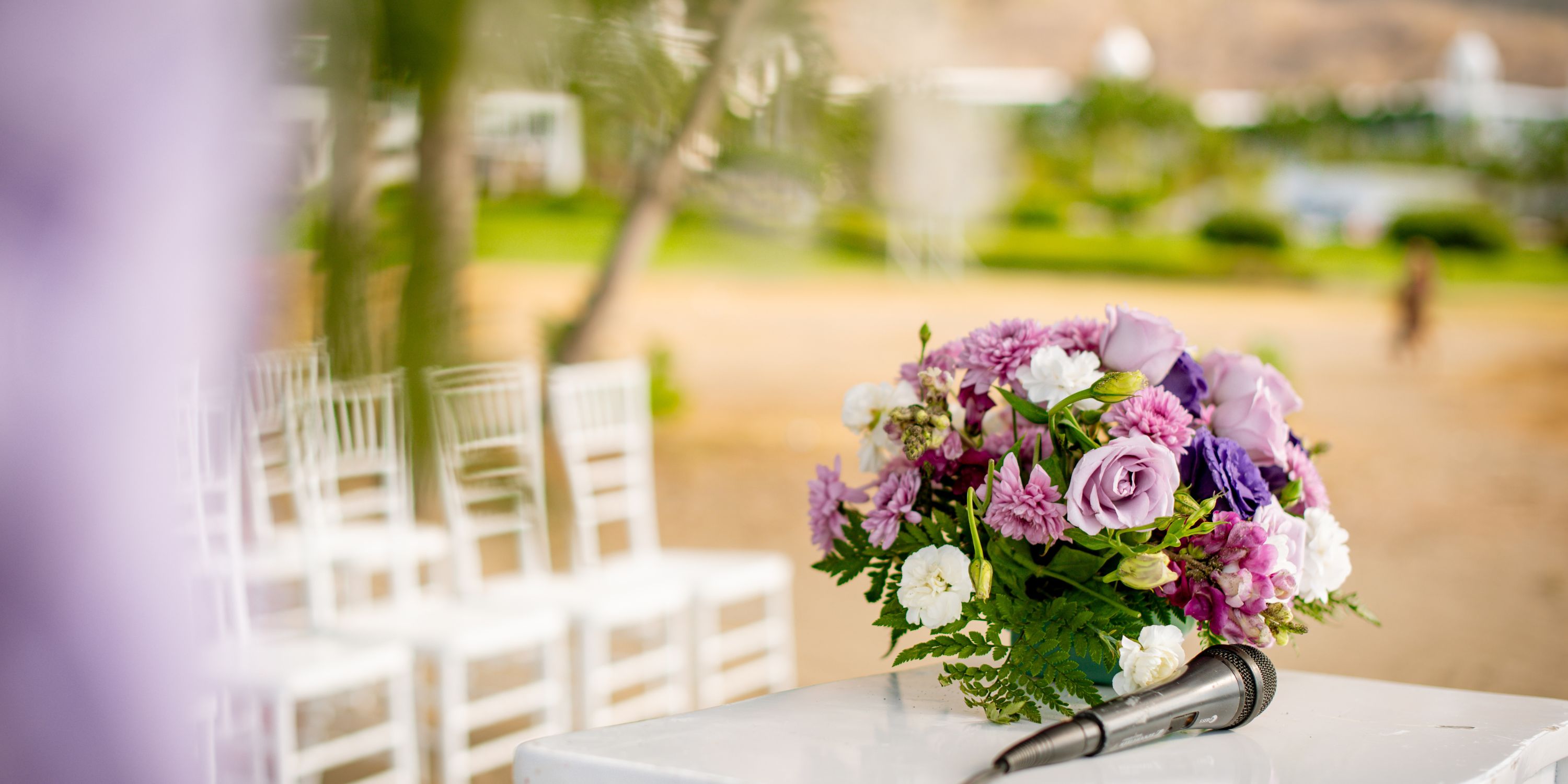 Bouquet of purple and white flowers at a destination wedding in Hotel Riu Guanacaste, chairs behind.