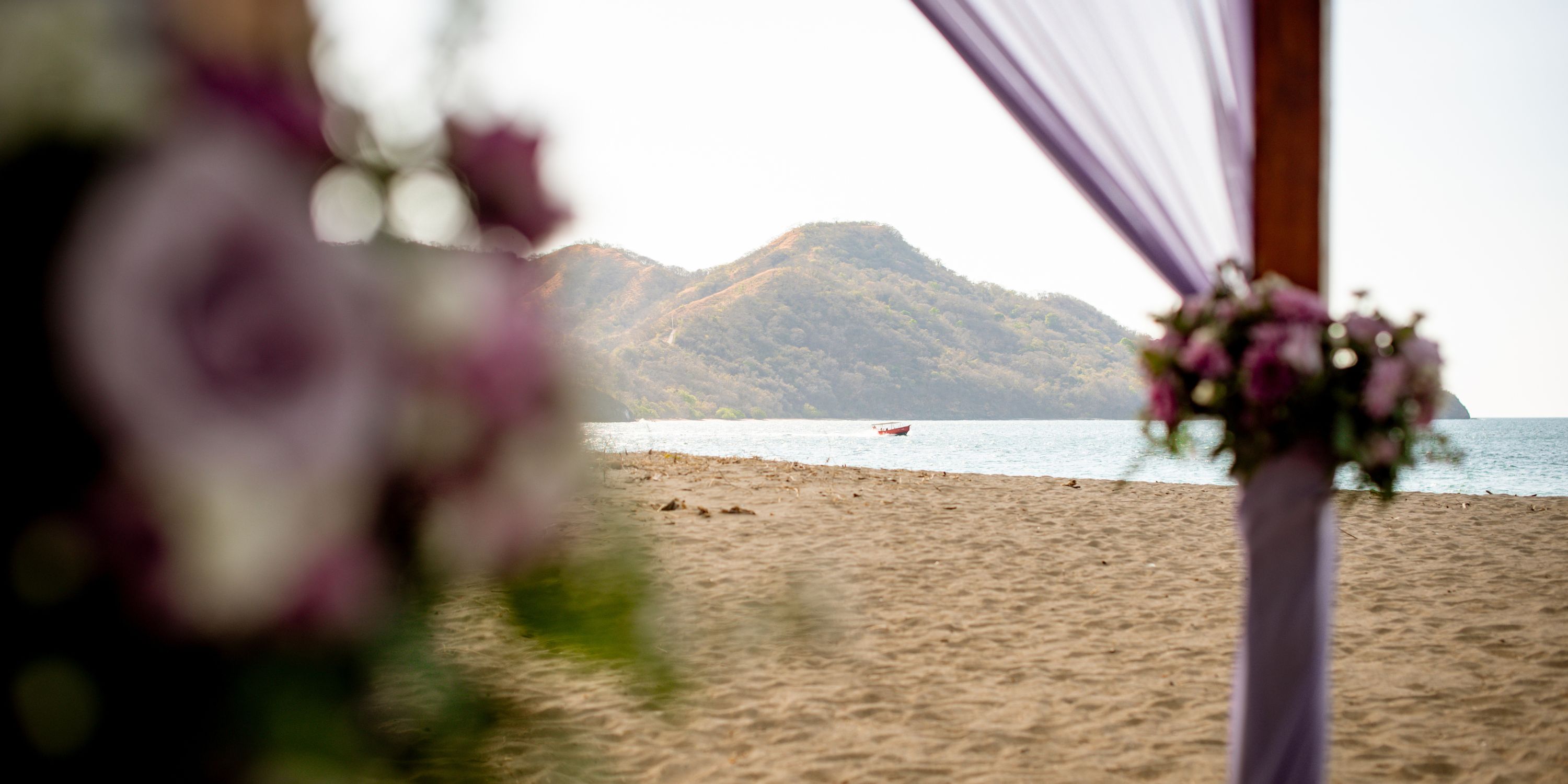 Hotel Riu Guanacaste: ideal destination wedding spot with sandy beach, mountains, boat, and flowers.