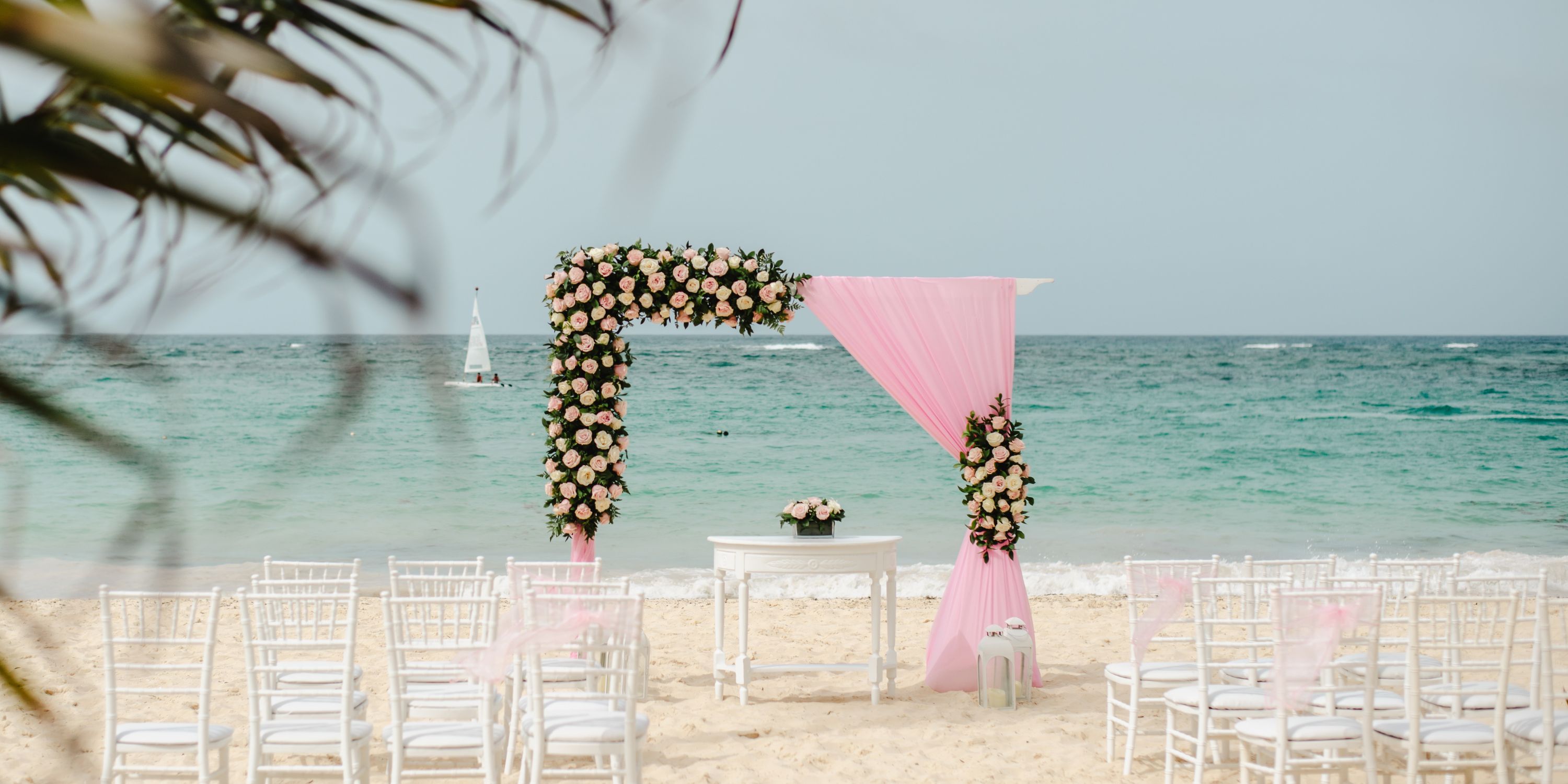 Destination wedding on the beach at Hotel Riu Palace Macao with a pink and white floral arch by the ocean.