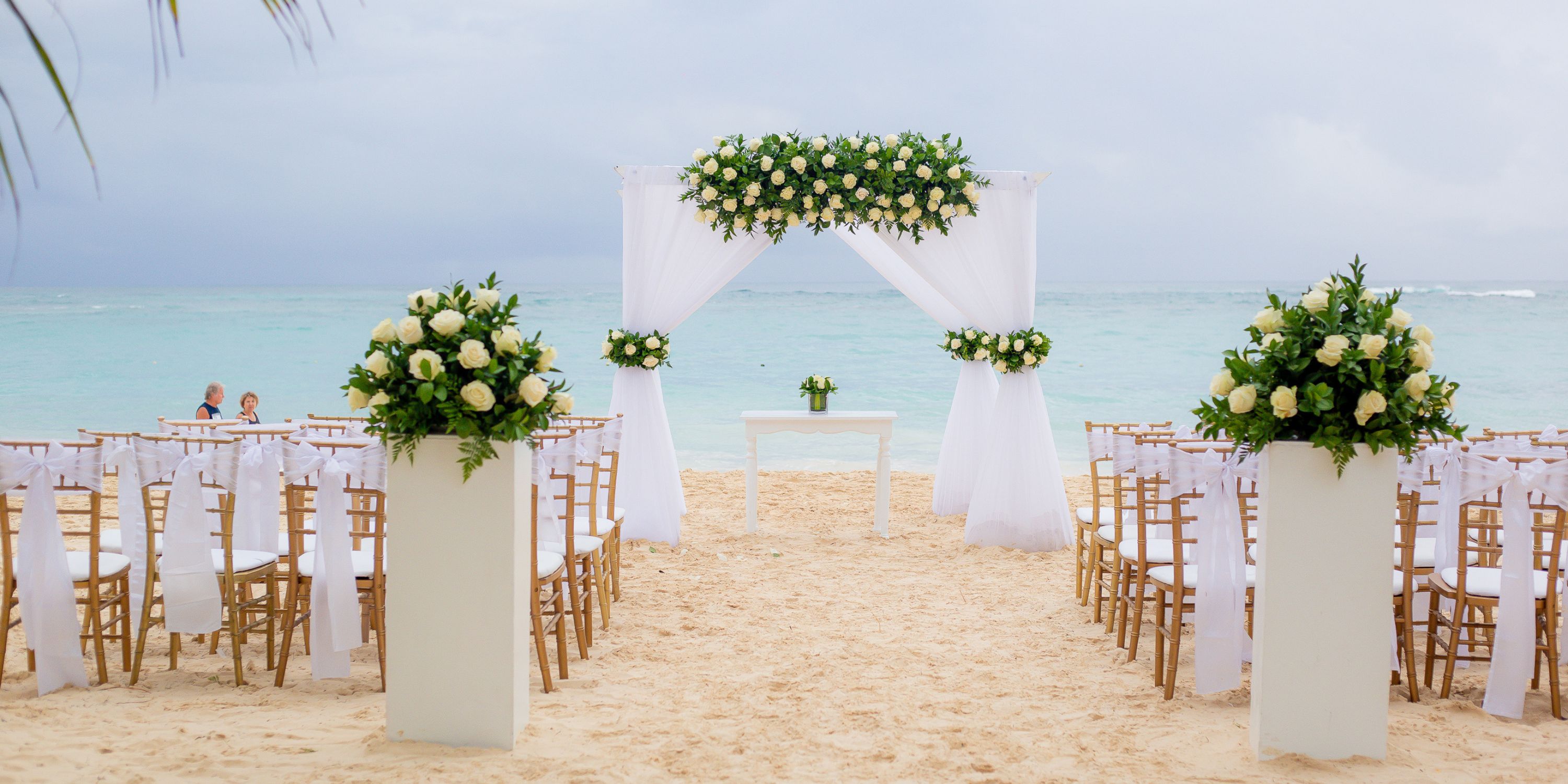 Destination wedding setup at Hotel Riu Palace Macao with white chairs, floral accents, and oceanfront arch.
