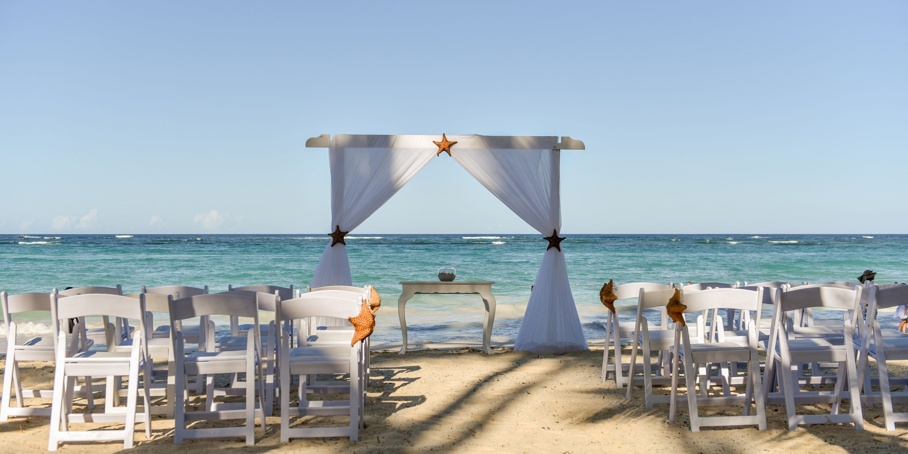 White chairs and a canopy set up on the beach at Hotel Riu Palace Bavaro for a destination wedding.