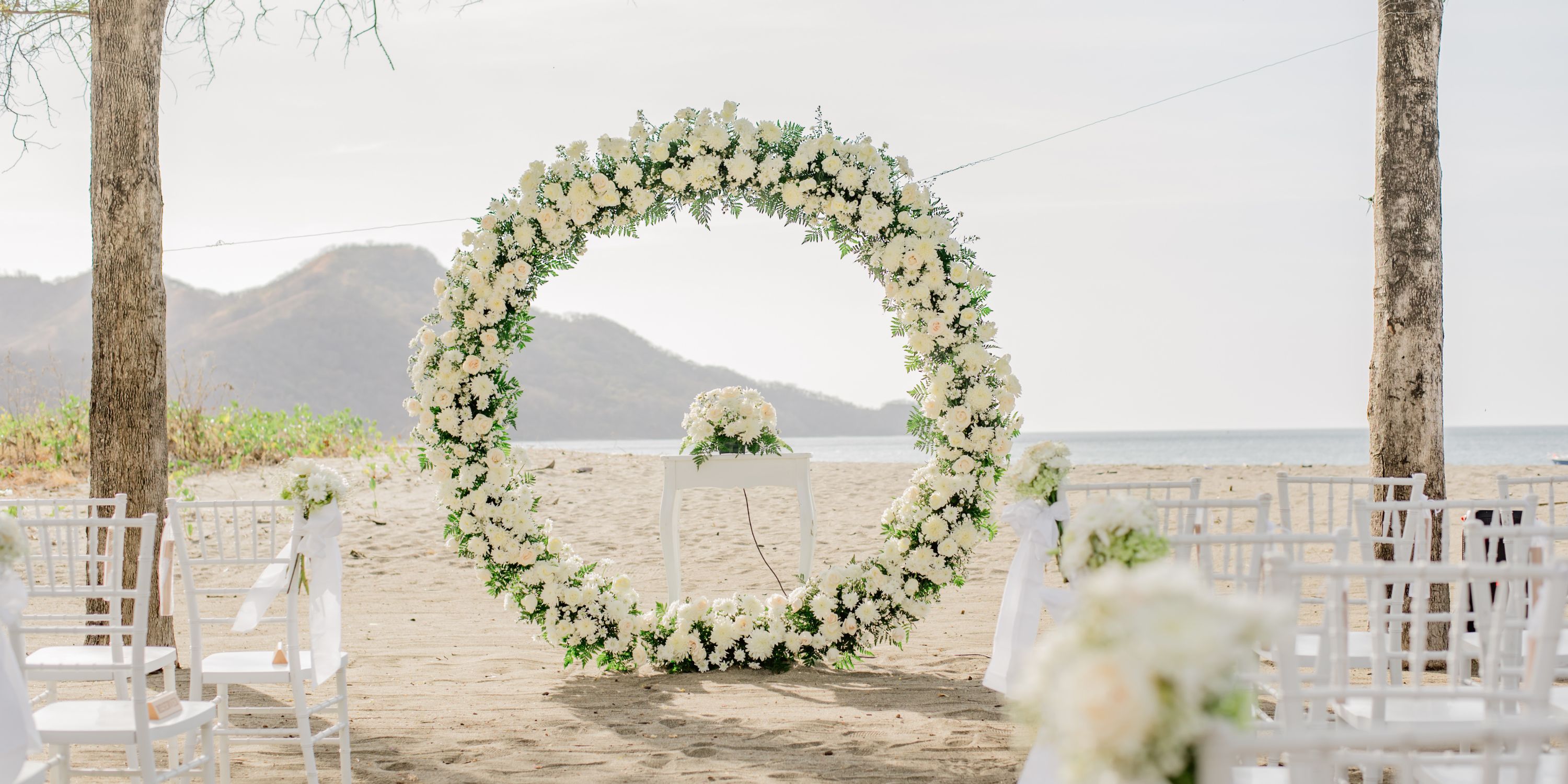 Destination wedding ceremony at Hotel Riu Palace Costa Rica with floral arch, seating, and mountain views.