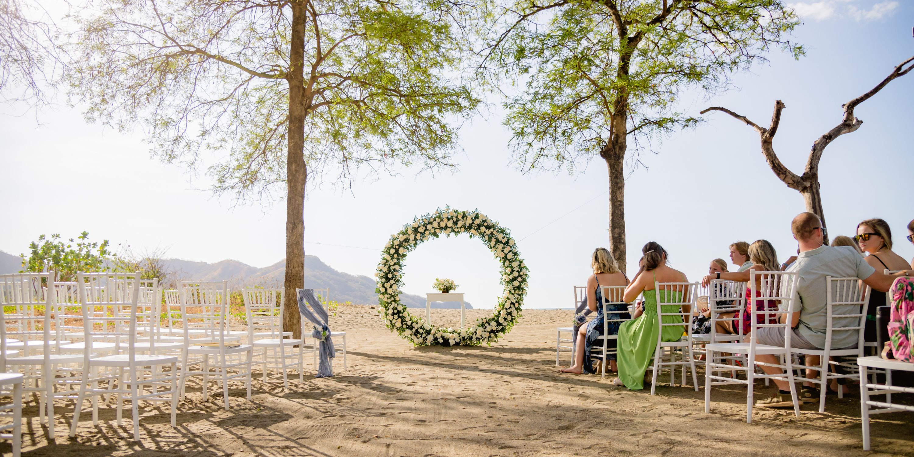 White chairs in rows and a floral arch arranged for a destination wedding at Hotel Riu Palace Costa Rica.