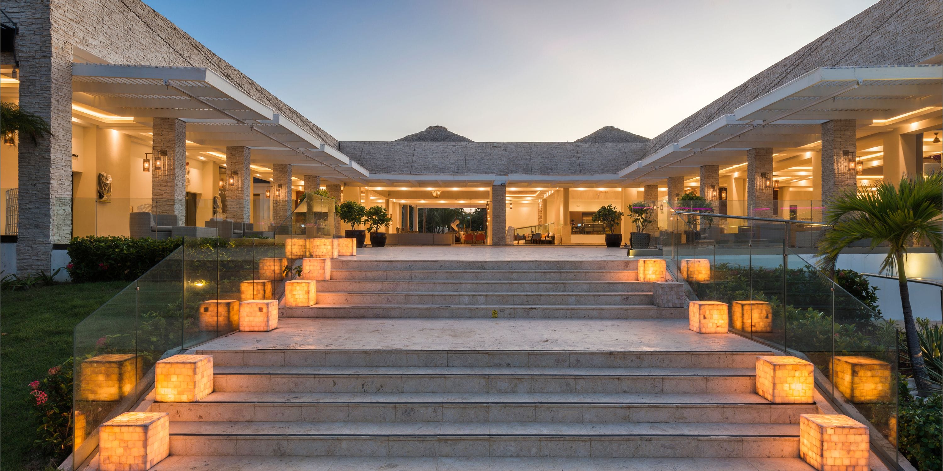 Lanterns glow at dusk on a stone stairway, perfect for a destination wedding entrance.