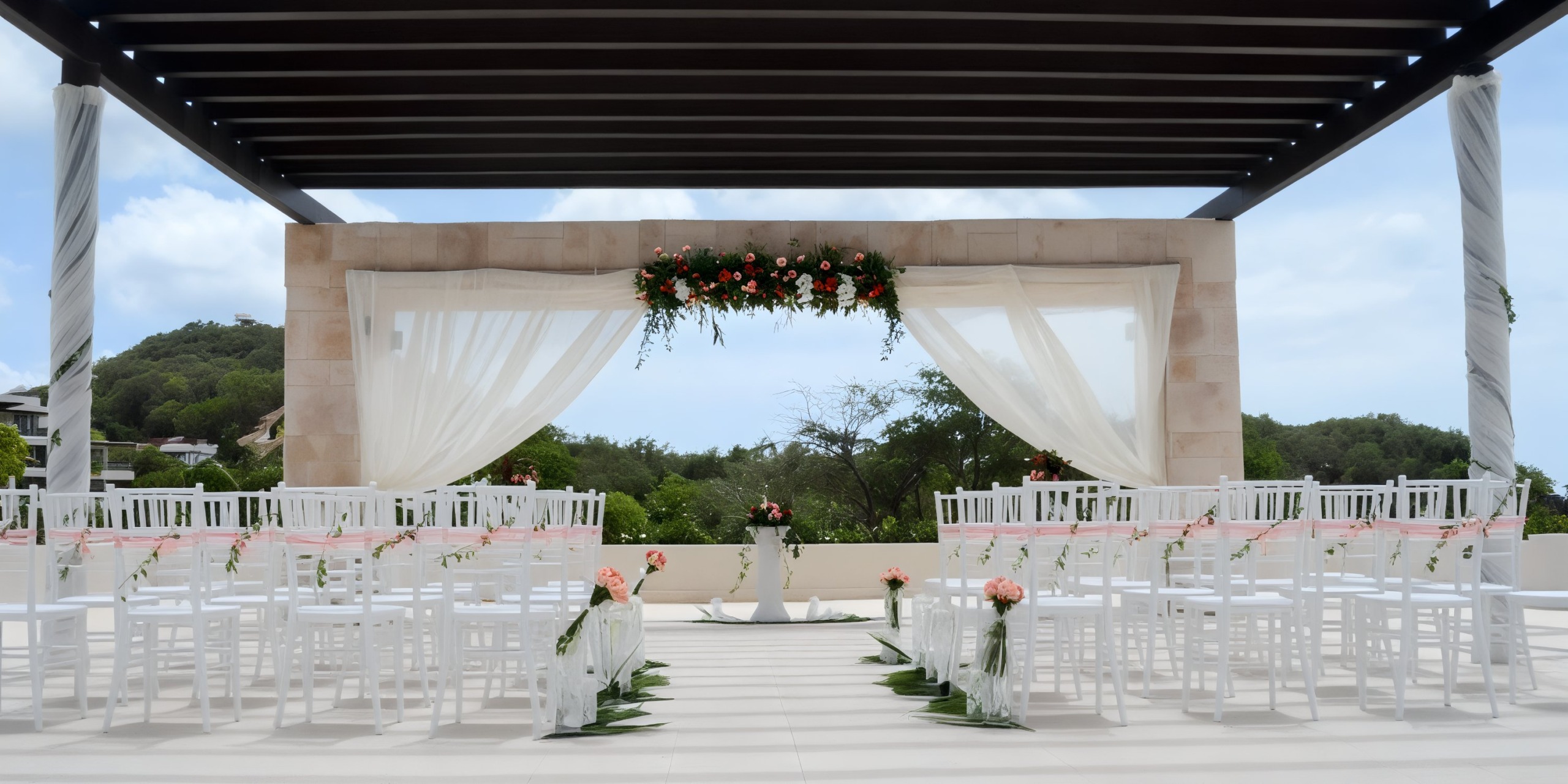 The destination wedding setup at Royalton St. Lucia features elegant white chairs, beautiful floral decor, and a gracefully draped canopy.