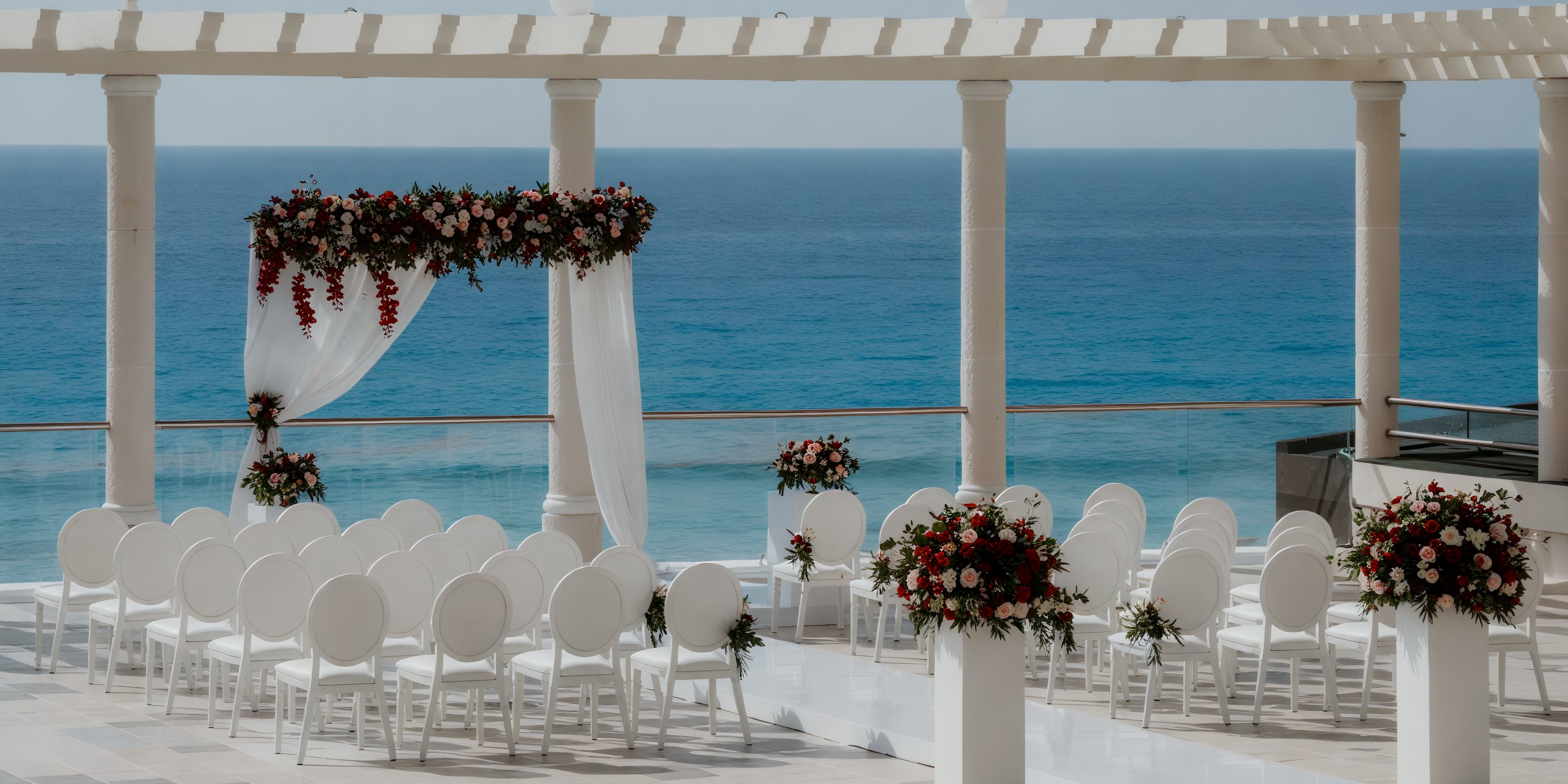 Destination wedding at Sandos Cancun Resort featuring white chairs and a beautiful floral arch by the ocean.
