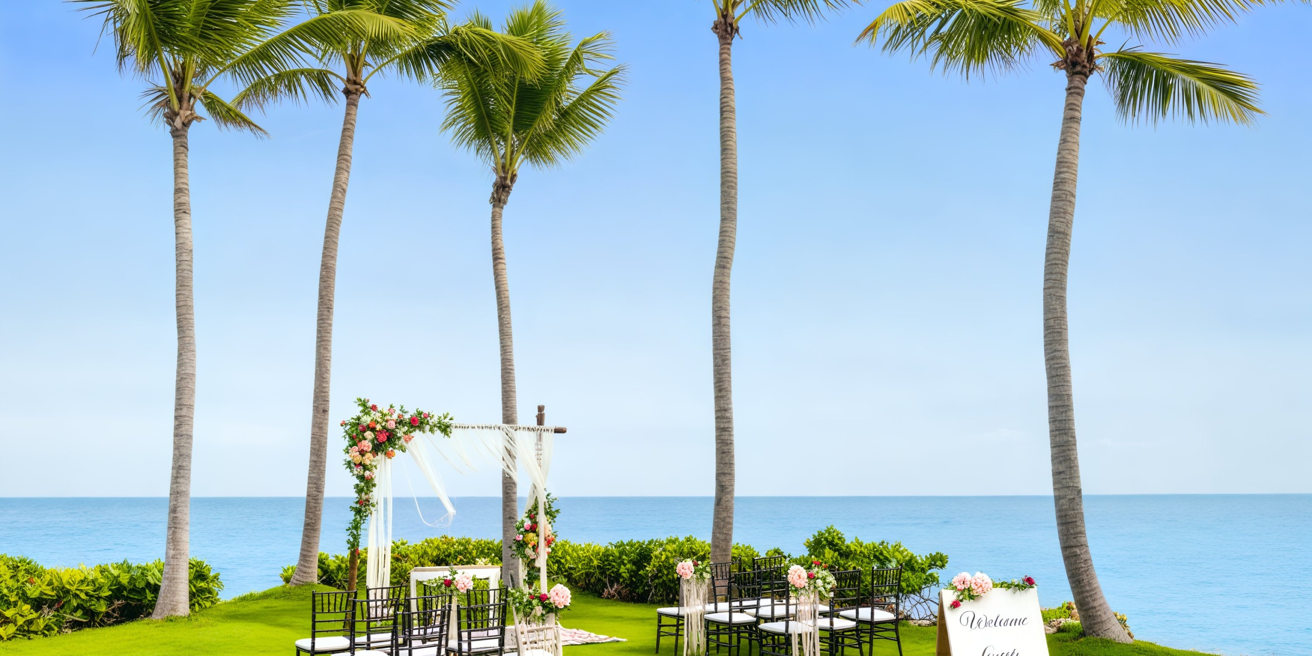 Sanctuary Cap Cana: A picturesque destination wedding setup featuring palm trees, vibrant flowers, and oceanfront seating.