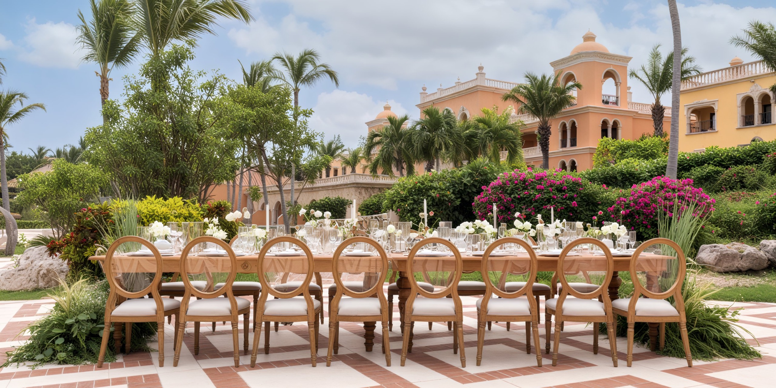 Sanctuary Cap Cana offers an elegant outdoor table setup with chairs nestled amidst lush greenery and vibrant flowers, creating the perfect backdrop for a destination wedding.