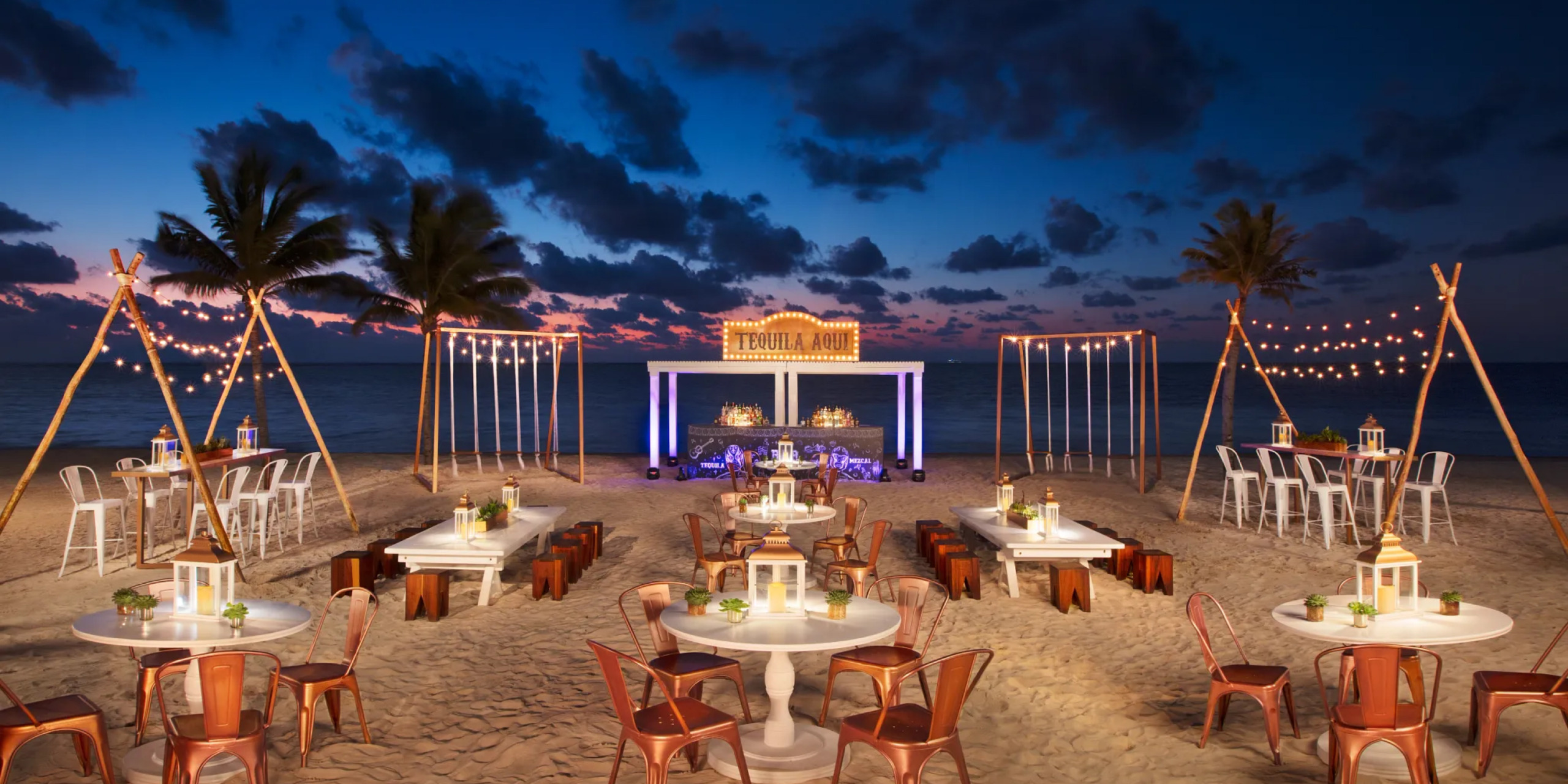 Gorgeous beach venue with neon decor and tables set up for a destination wedding