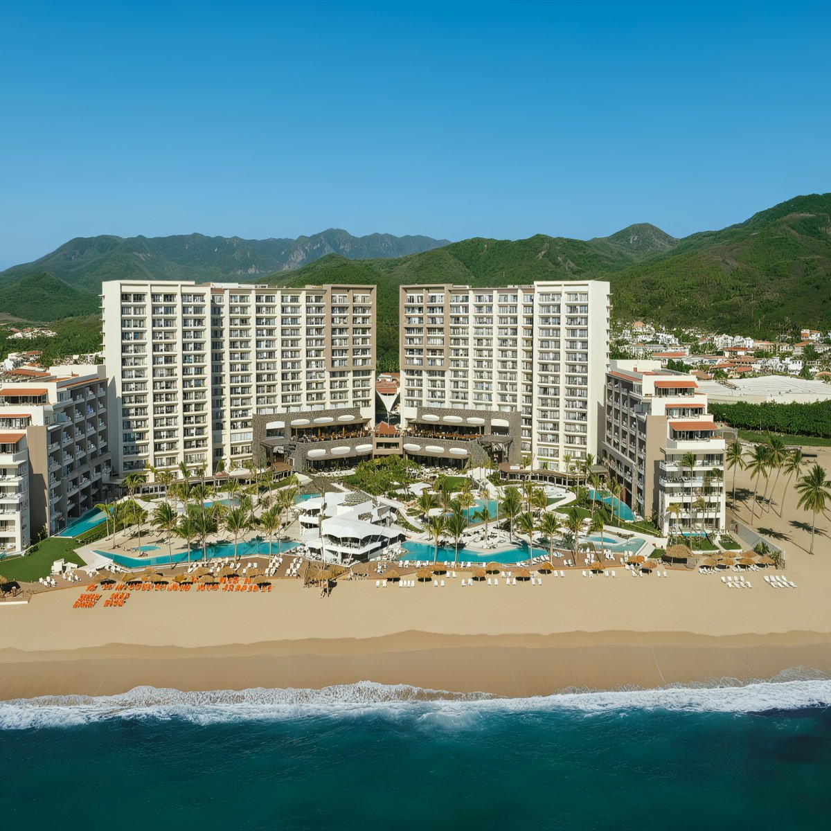Aerial view of Secrets Vallarta Bay, a sprawling beachfront resort featuring multiple pools and palm trees, nestled against a backdrop of lush green hills and a clear blue sky.