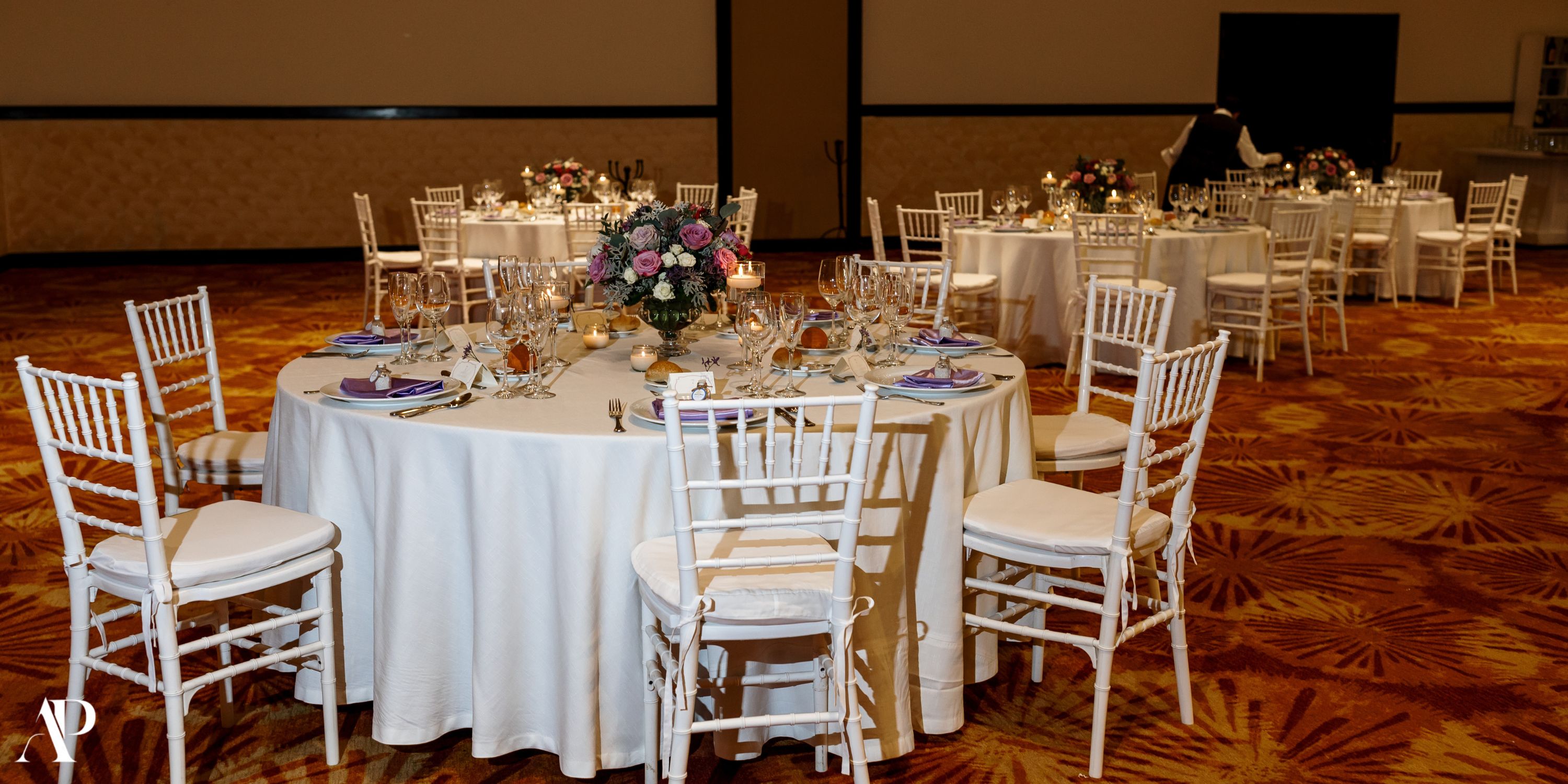 Secrets Vallarta Bay banquet hall arranged for a destination wedding with round tables and floral centerpieces.