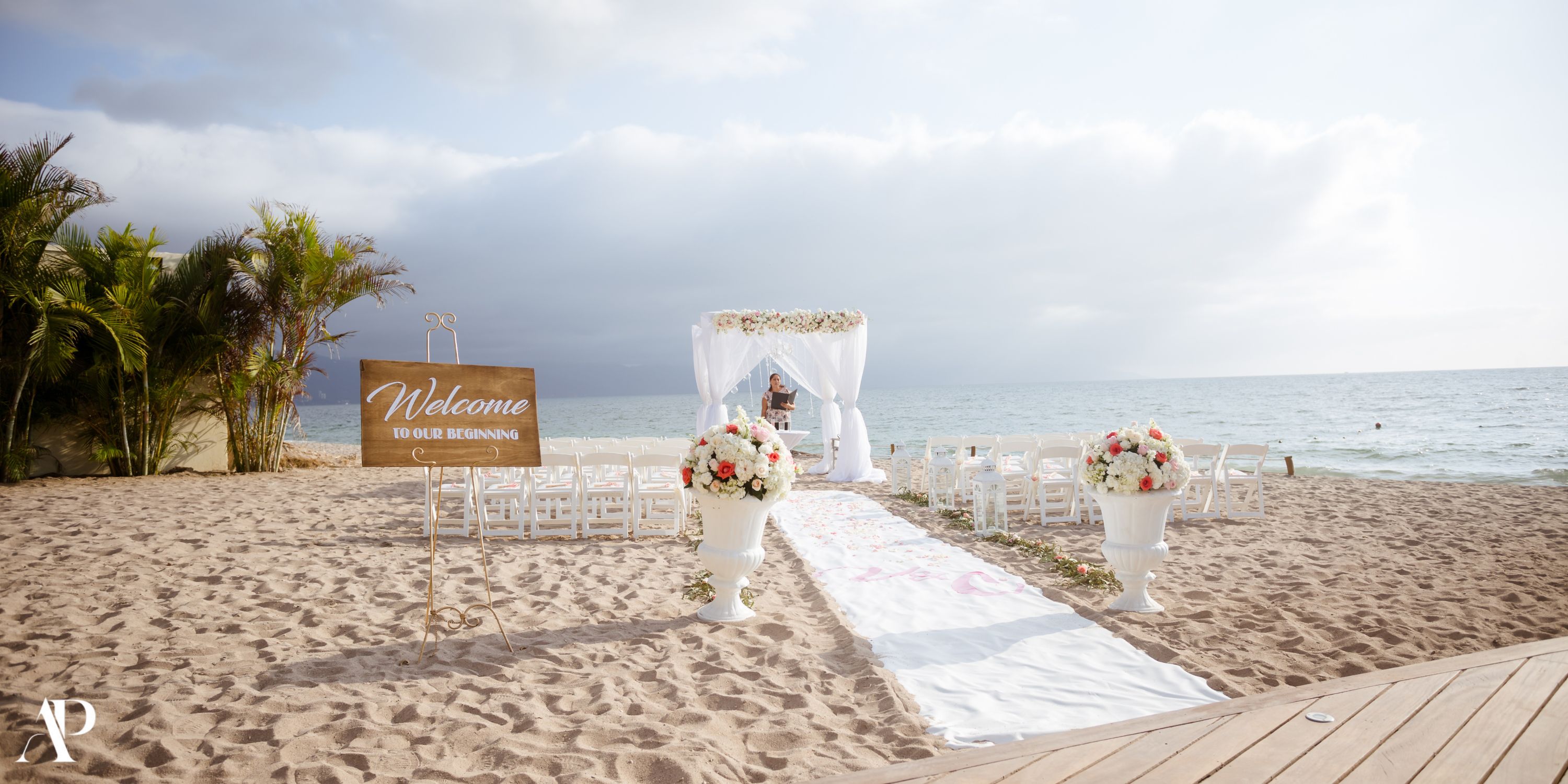 Destination wedding setup at Secrets Vallarta Bay with chairs, florals, and a “Welcome” sign by the sea.