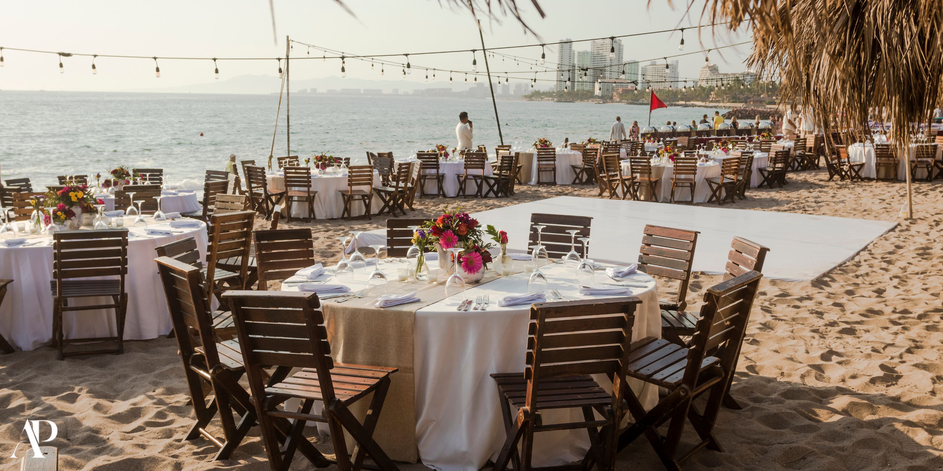 Destination wedding setup with round tables and chairs on sand at Secrets Vallarta Bay by the ocean.