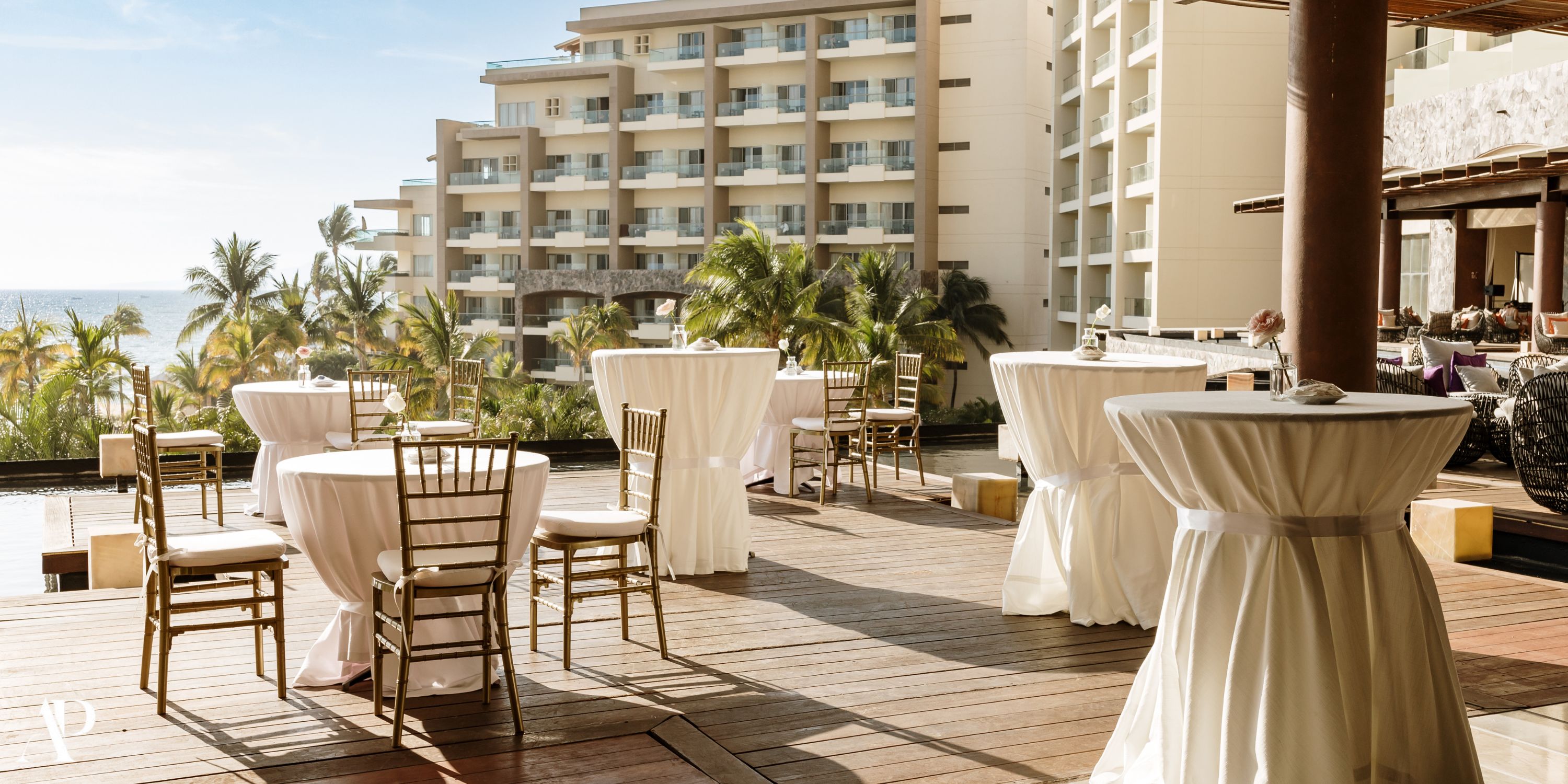 Terrace at Secrets Vallarta Bay set up for a destination wedding with cocktail tables, chairs, and palm views.