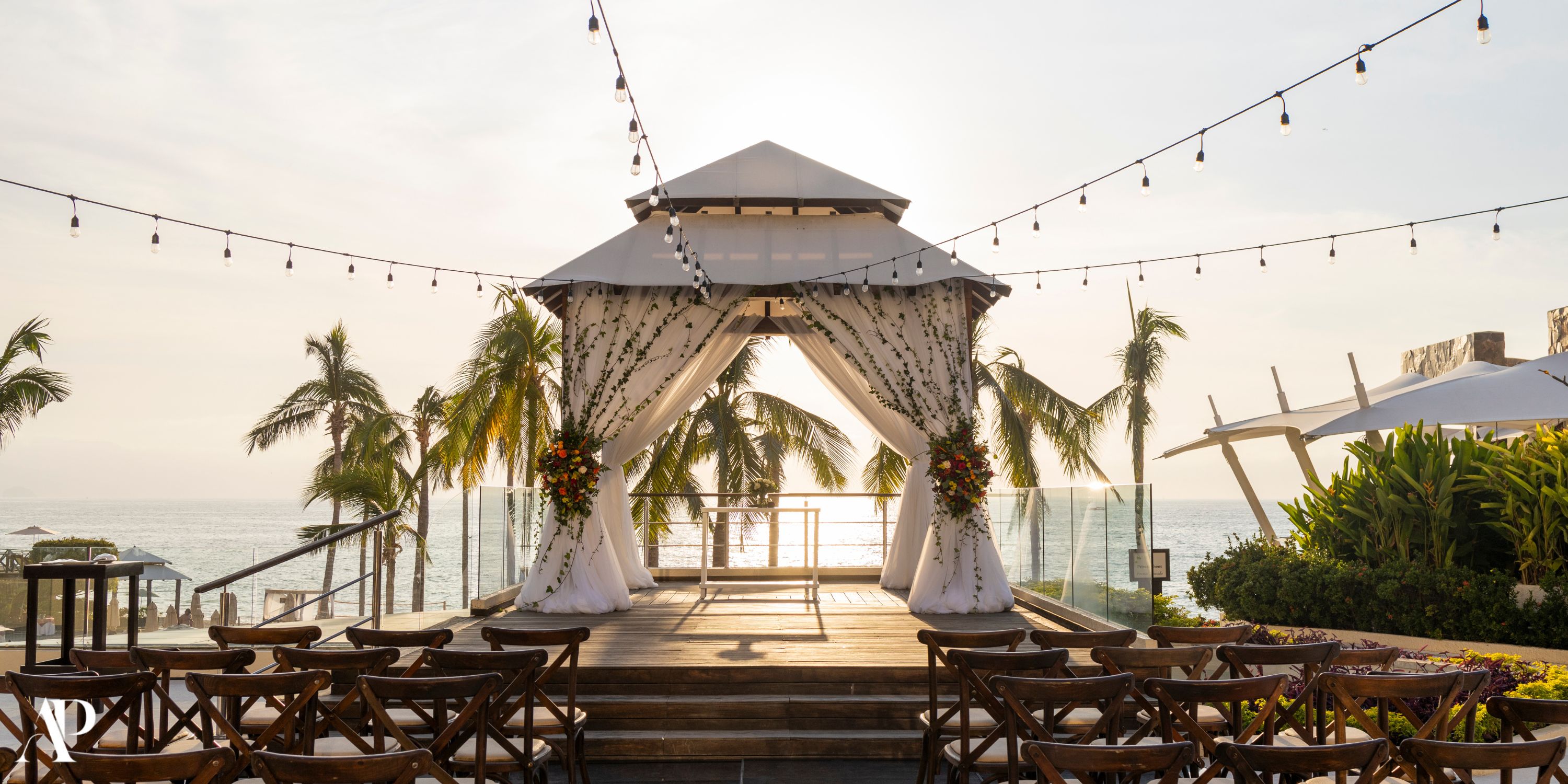 Gazebo at Secrets Vallarta Bay set for a destination wedding with draped fabric, lights, and sunset ocean view.