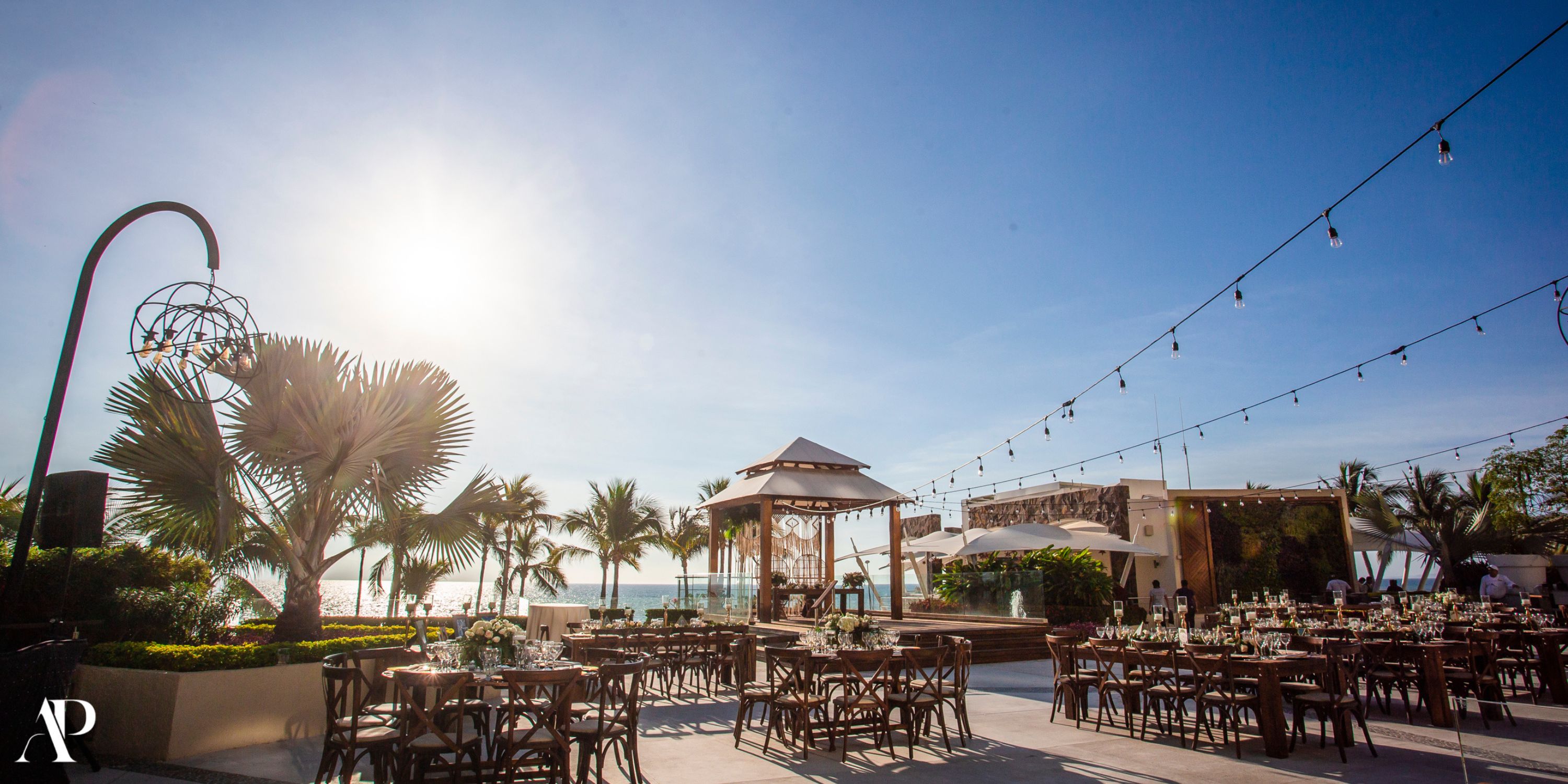 Secrets Vallarta Bay: outdoor wedding venue with wooden tables, palm trees, and romantic string lights.