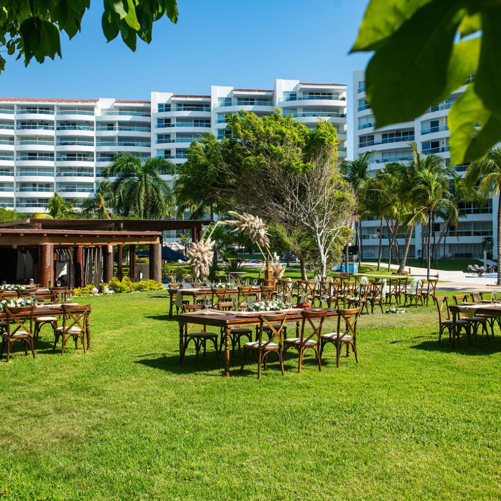 An enchanting outdoor wedding setup on a lawn, featuring elegantly arranged chairs and tables with a scenic building backdrop.