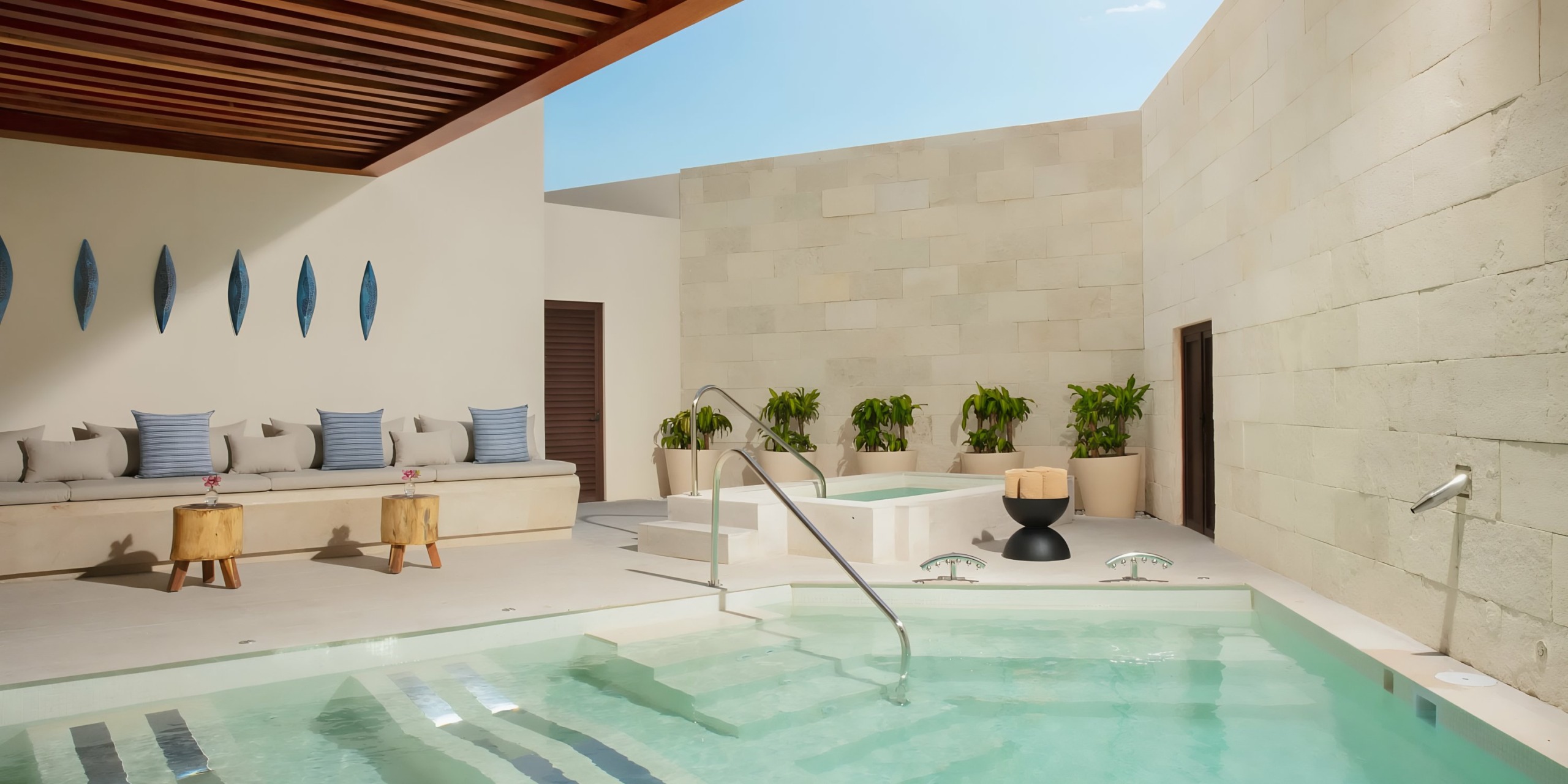 Modern Dreams Aventuras Riviera Maya outdoor pool area with seating and decorative elements within a walled courtyard.