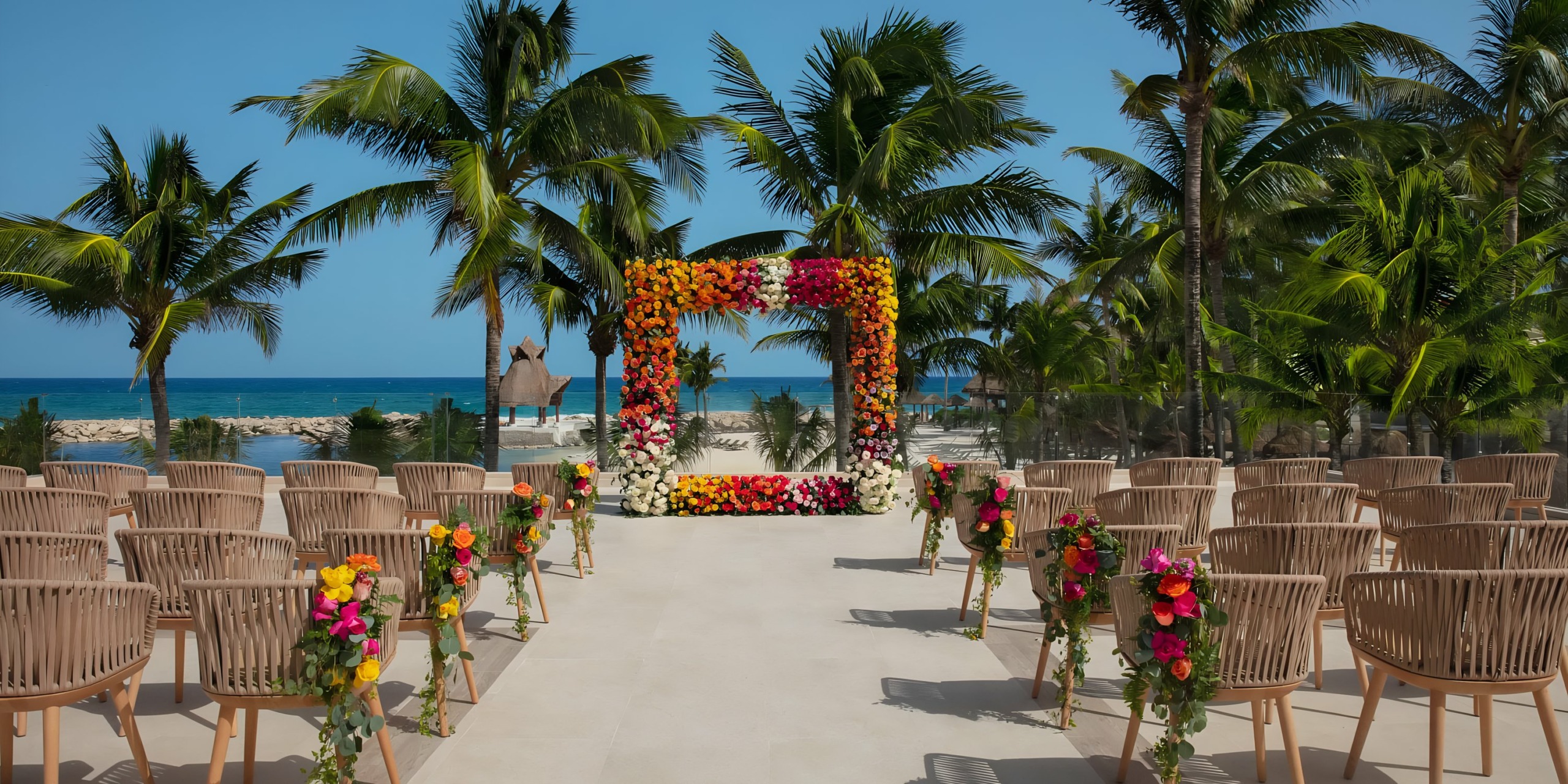 Dreams Aventuras Riviera Maya wedding setup with floral arch and rows of chairs facing the ocean.
