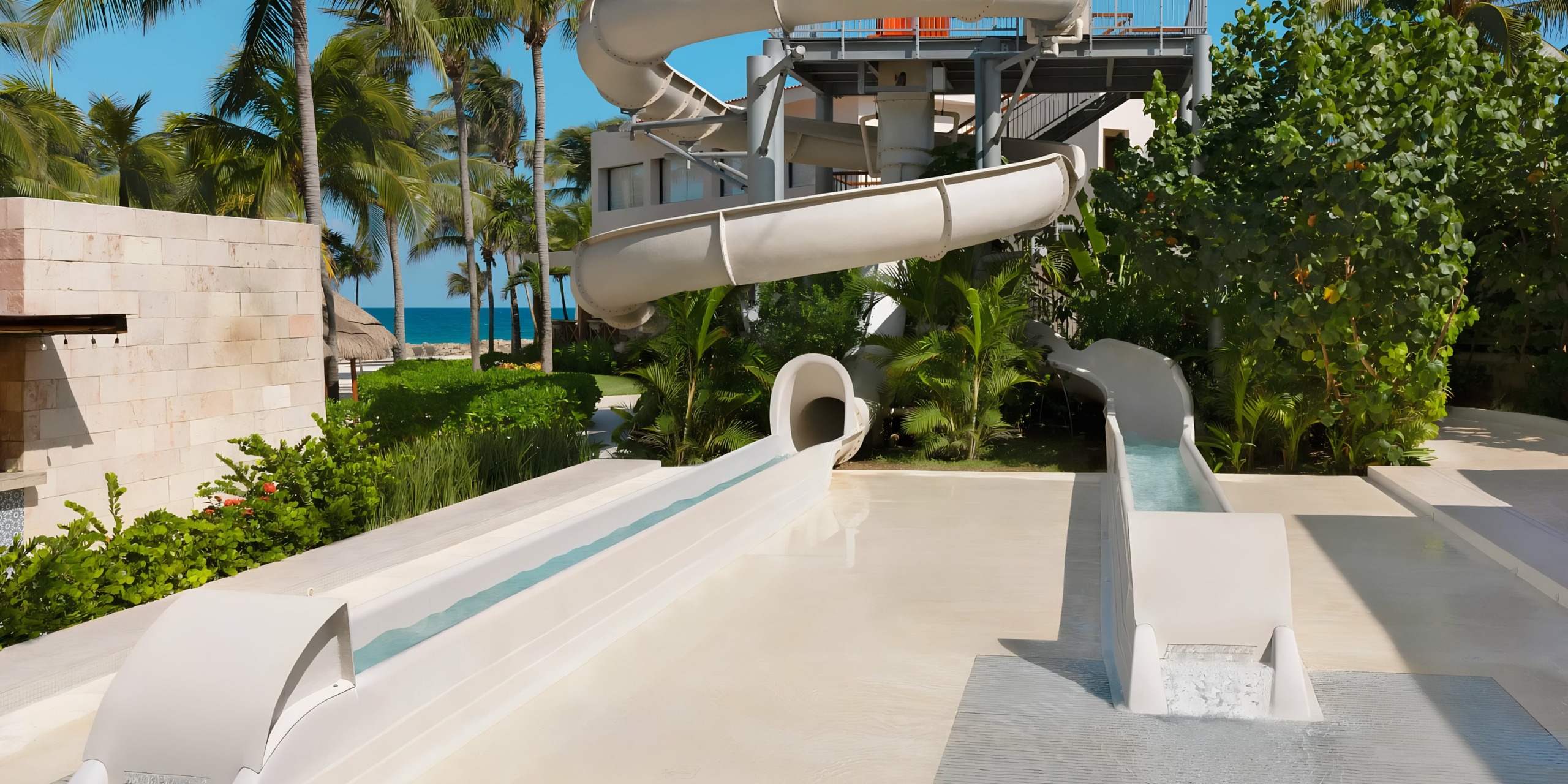 Dreams Aventuras Riviera Maya slides at a tropical resort with the ocean in the background.