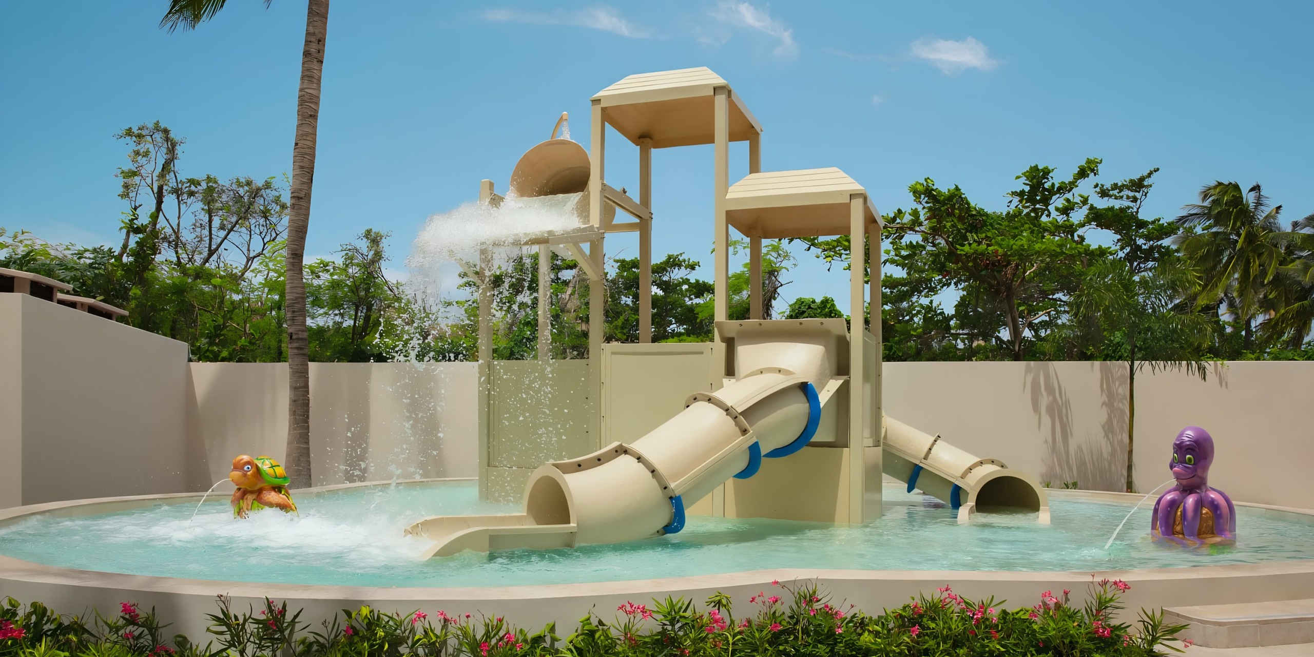 Children playing in the Dreams Aventuras Riviera Maya pool with slides and spray features.