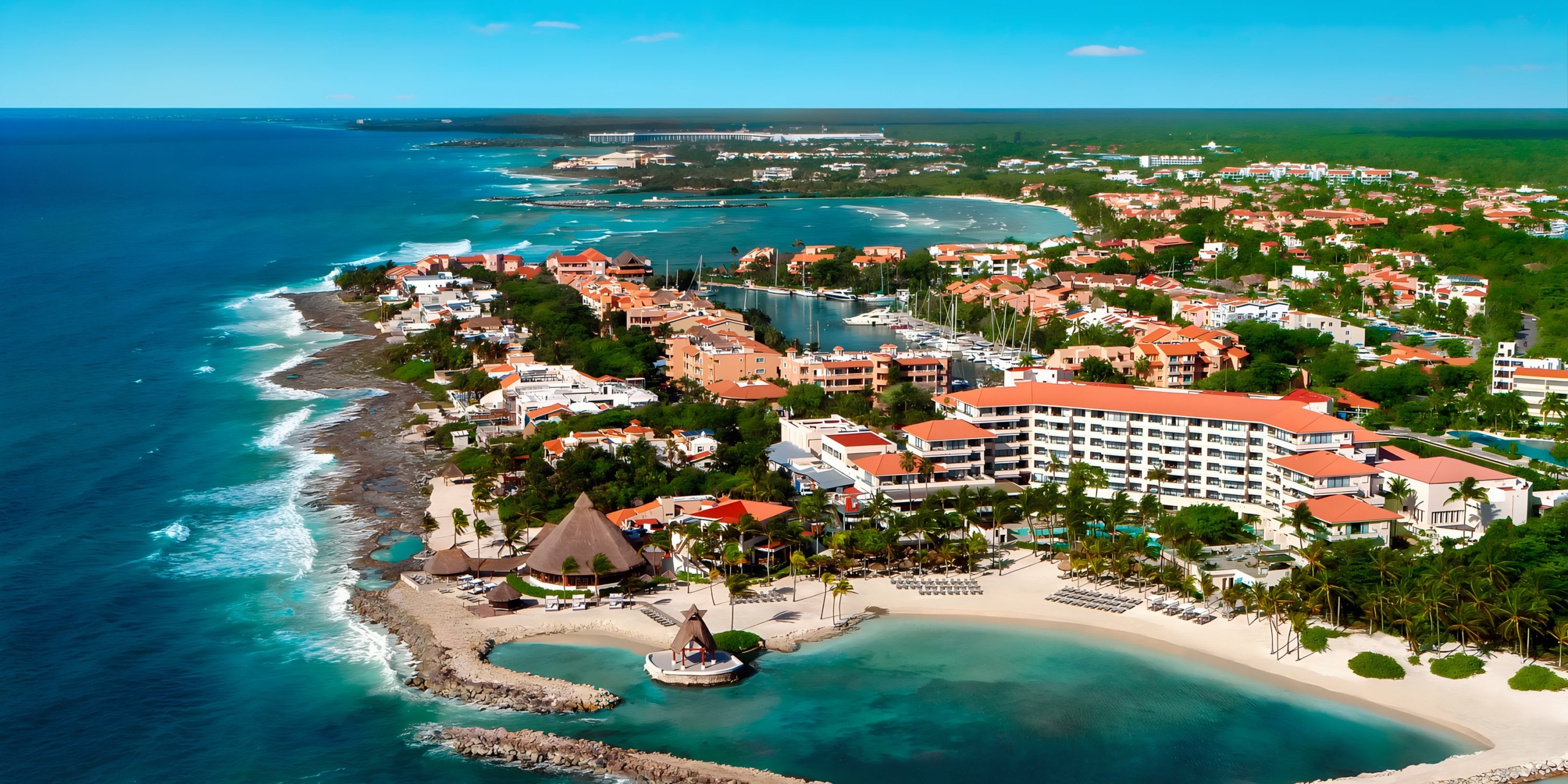 Aerial view of Dreams Aventuras Riviera Maya with clear blue waters, sandy beaches, and clustered buildings.