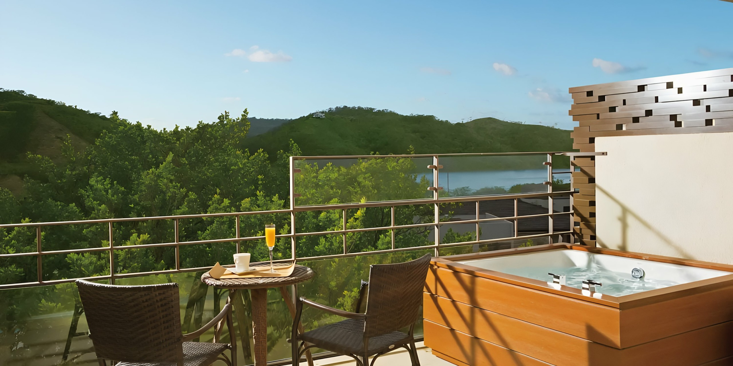 Dreams Las Mareas with a hot tub, overlooking a serene lake and green hills.