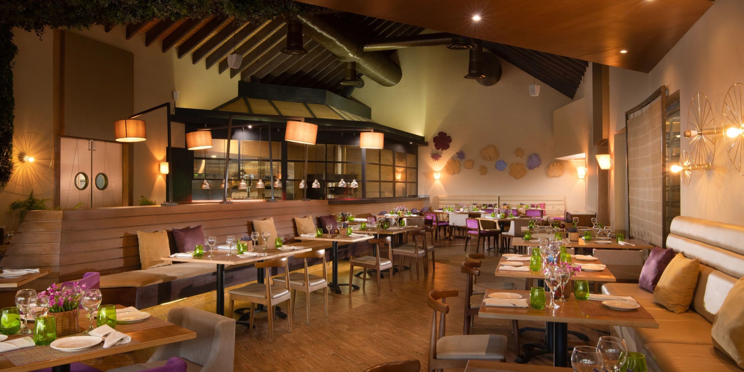 The Dreams Onyx restaurant features a modern interior with wooden floors, tables elegantly set for dining, and comfortable cushioned seating. The wall decor and warm lighting enhance the cozy atmosphere.