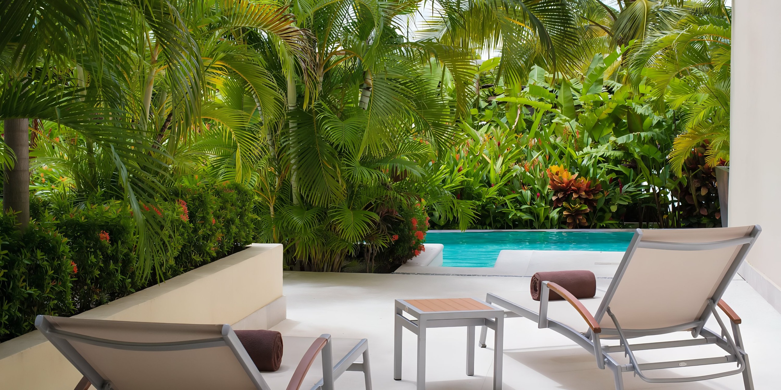 A serene wedding poolside retreat at Dreams Vallarta Bay with lush greenery and comfortable lounging chairs.