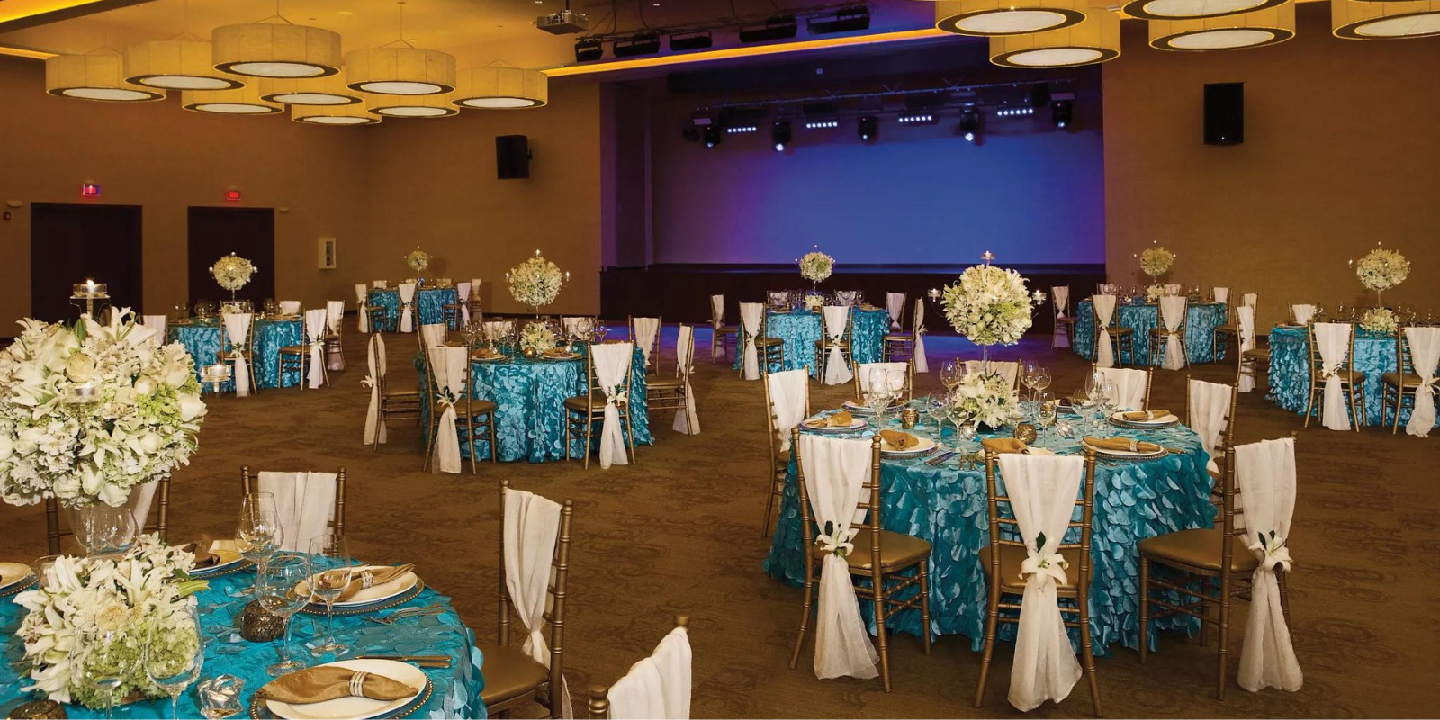 A large ballroom, perfect for a destination wedding, with blue and white tables and chairs at Dreams Las Mareas.
