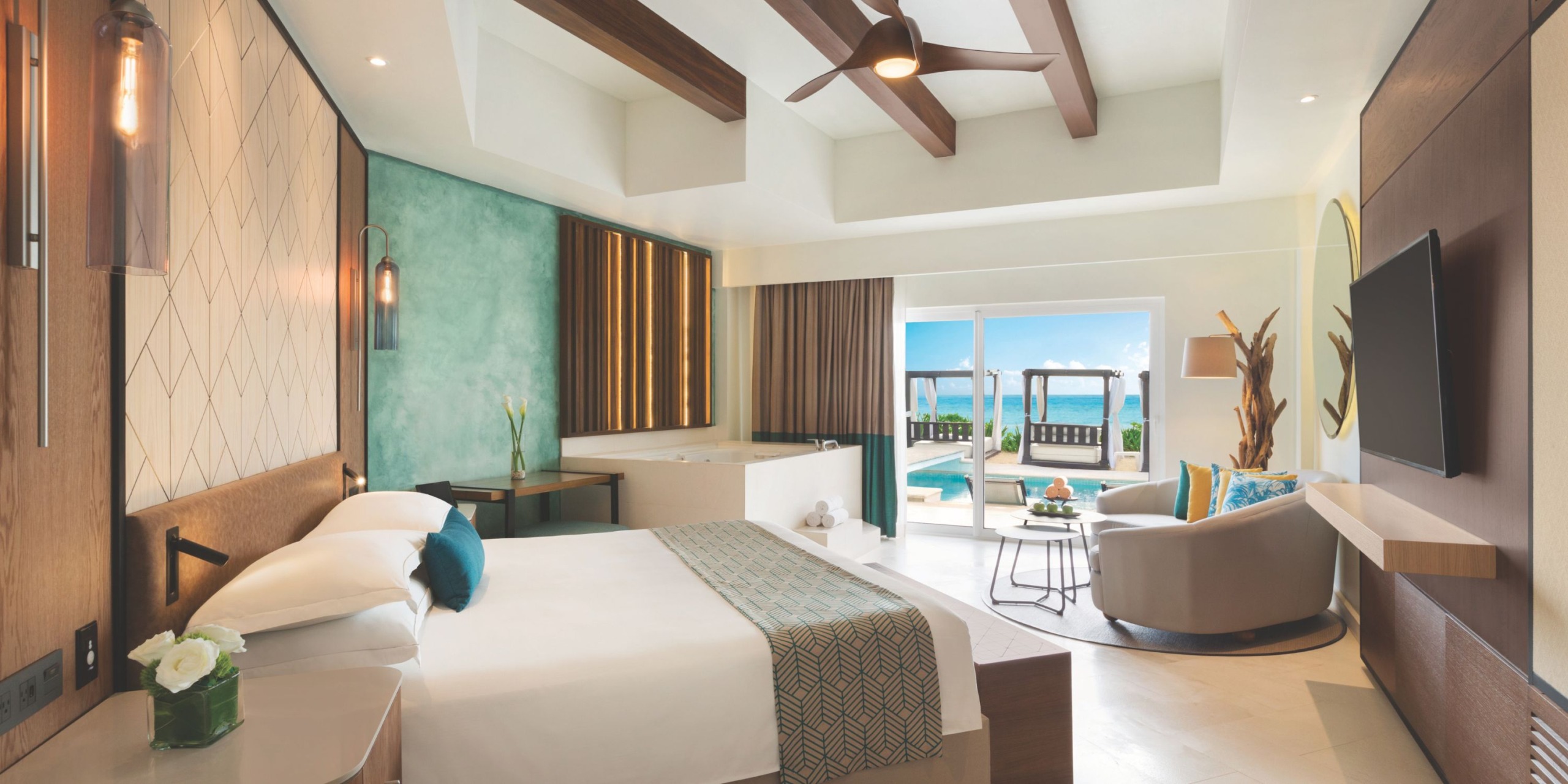 Experience a contemporary room at Hilton Playa del Carmen, featuring a double bed, ceiling fan, and comfortable sitting area. Enjoy the expansive window views that open up to a charming patio overlooking the pool.