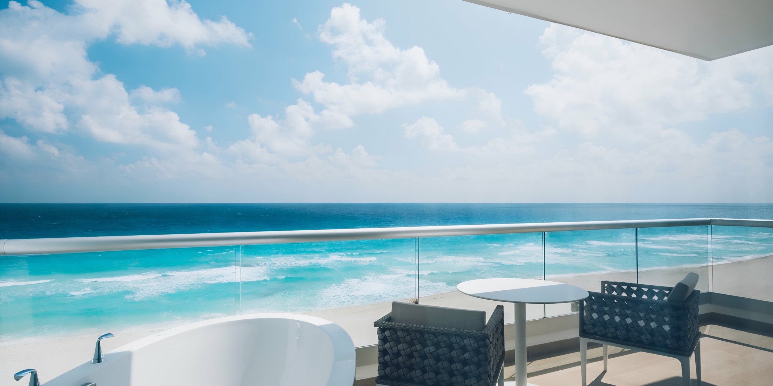 A serene ocean view from a balcony at the Iberostar Selection Cancun with outdoor seating and a bathtub.