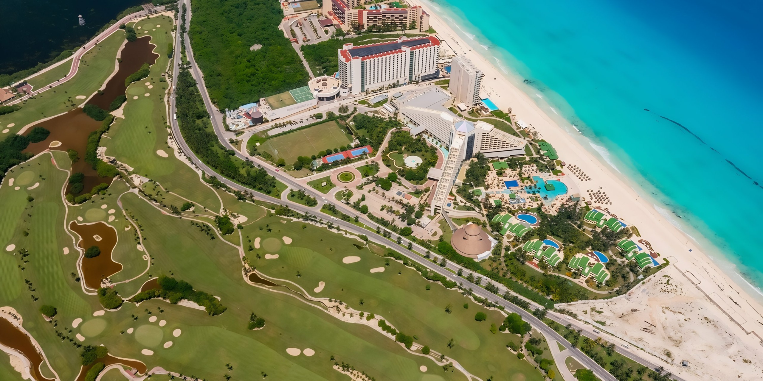 Aerial view of Iberostar Selection Cancun with a golf course, hotels, and a turquoise sea.